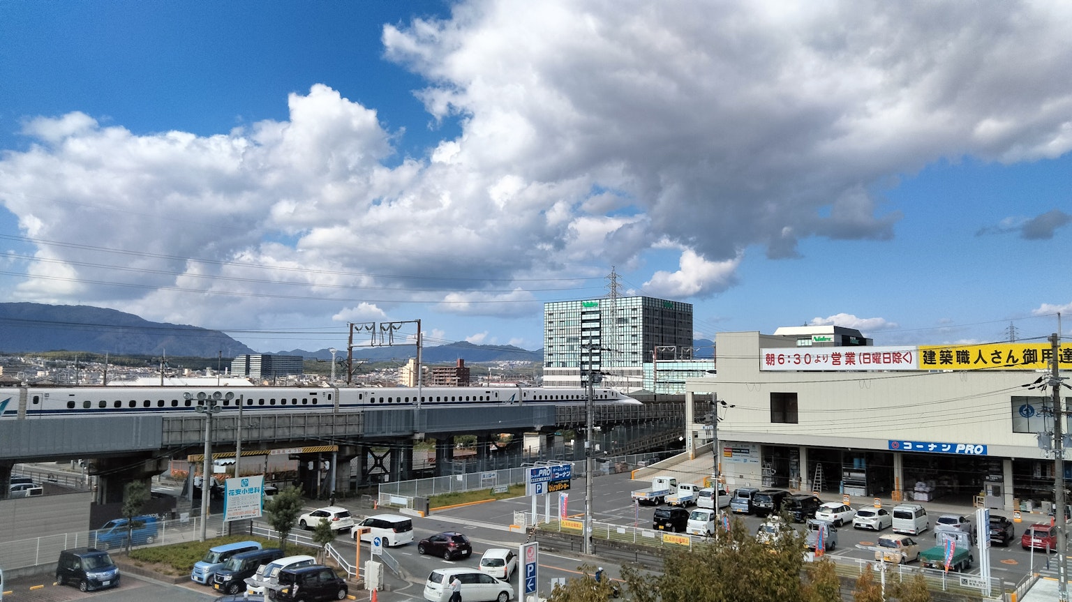 Paisaje urbano bajo un cielo azul con nubes blancas que presenta tráfico y edificios