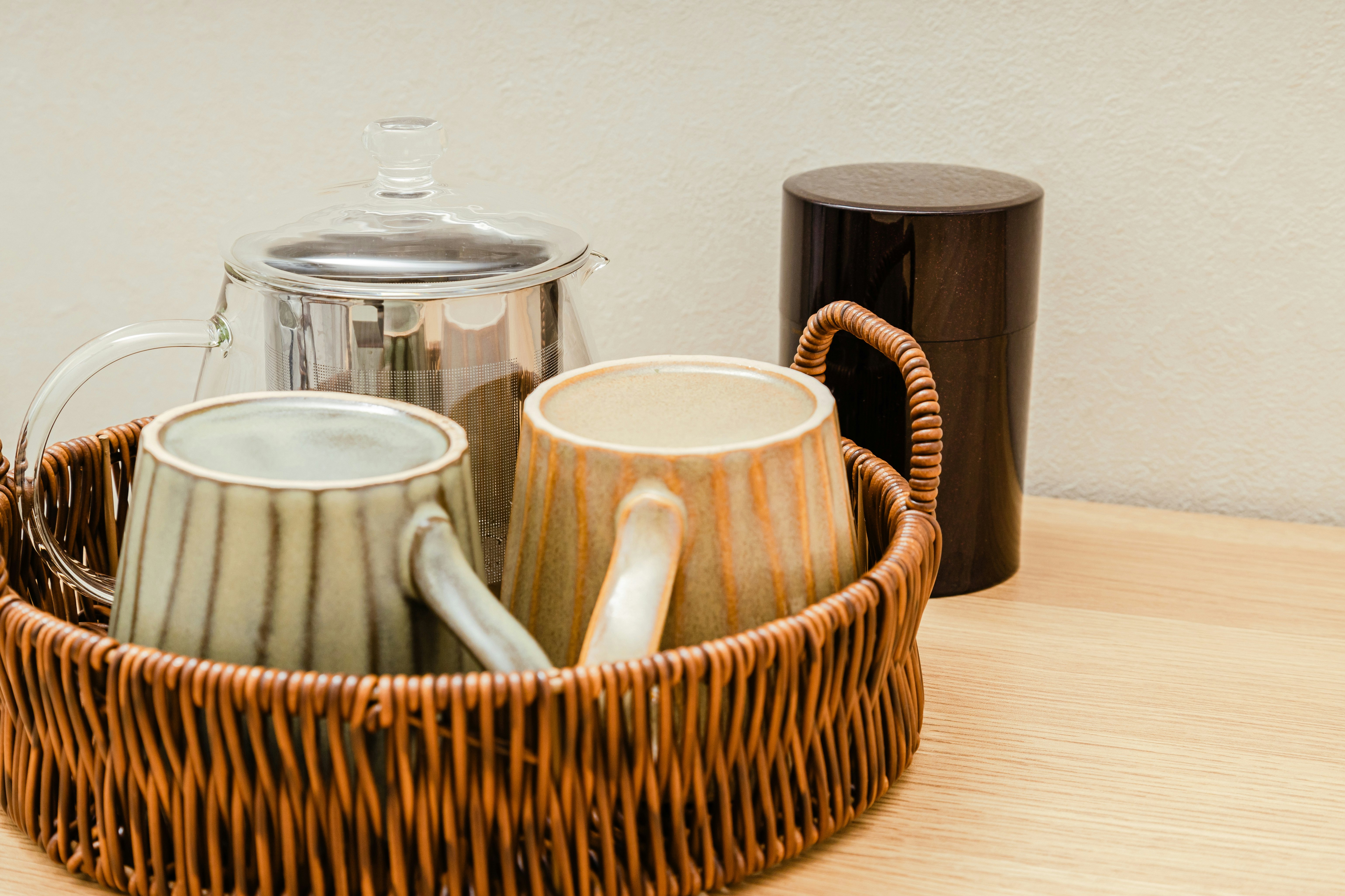 籐かごに入った急須と湯呑みのあるお茶のセット