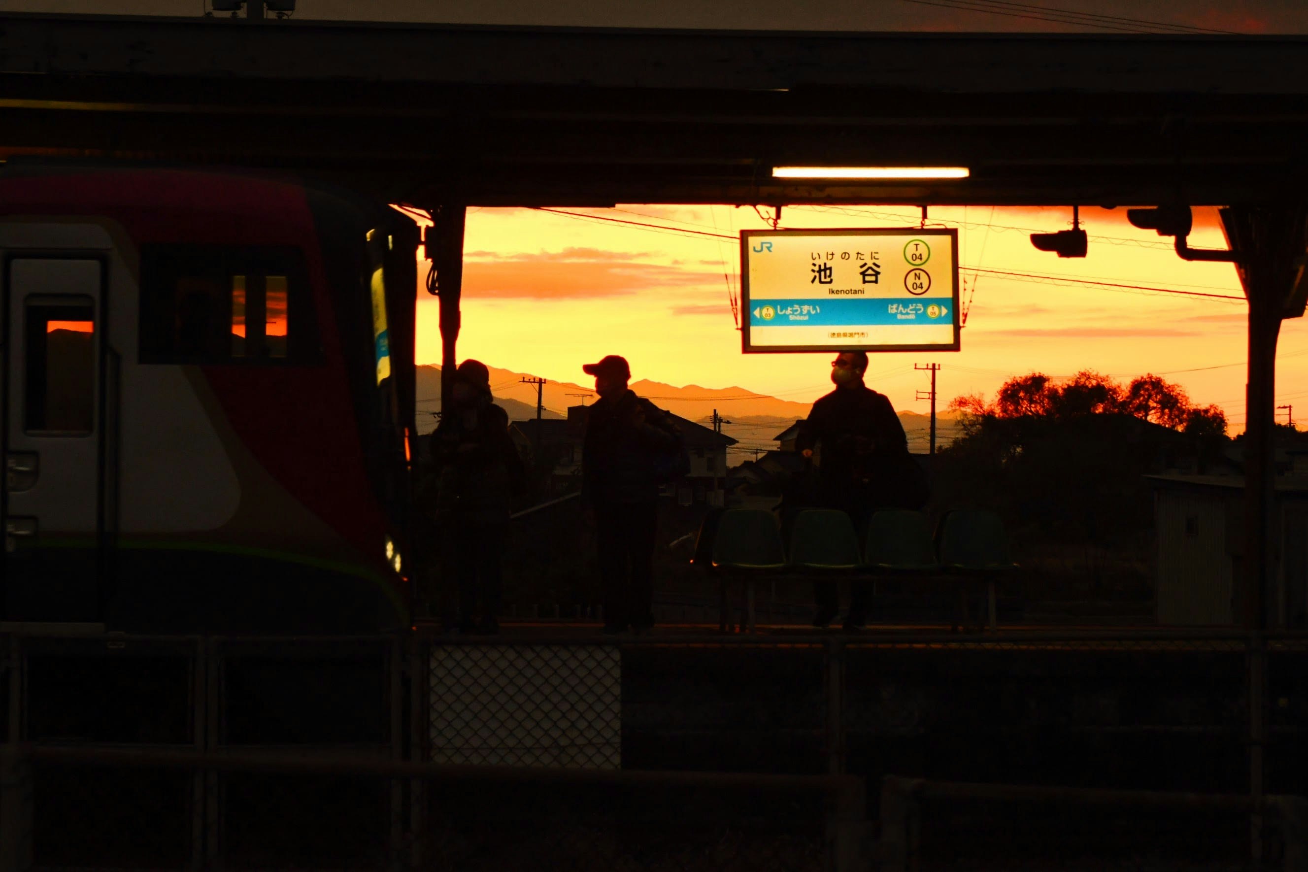 夕陽の駅ホームでシルエットになる人々の風景