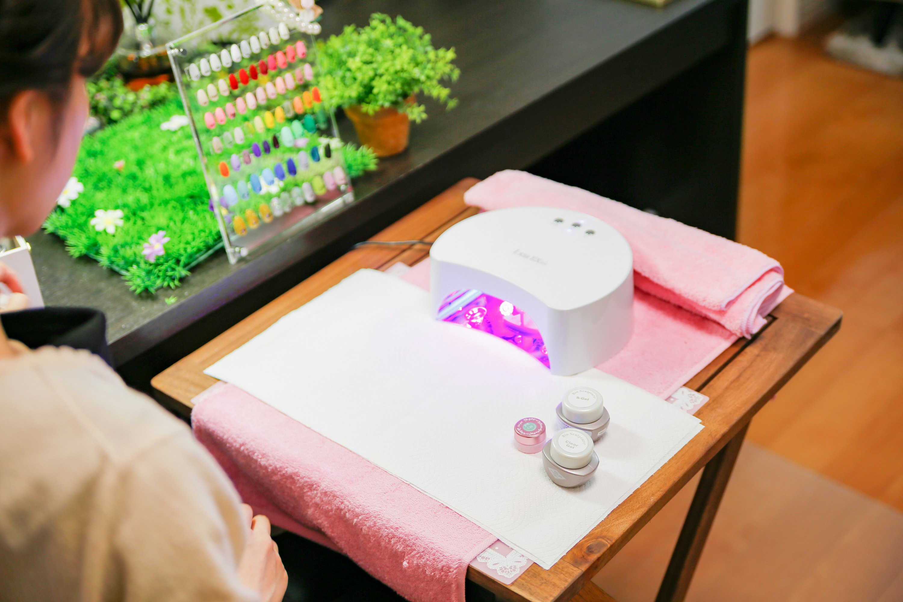 白いネイルライトで施術中のピンクタオルと小物
