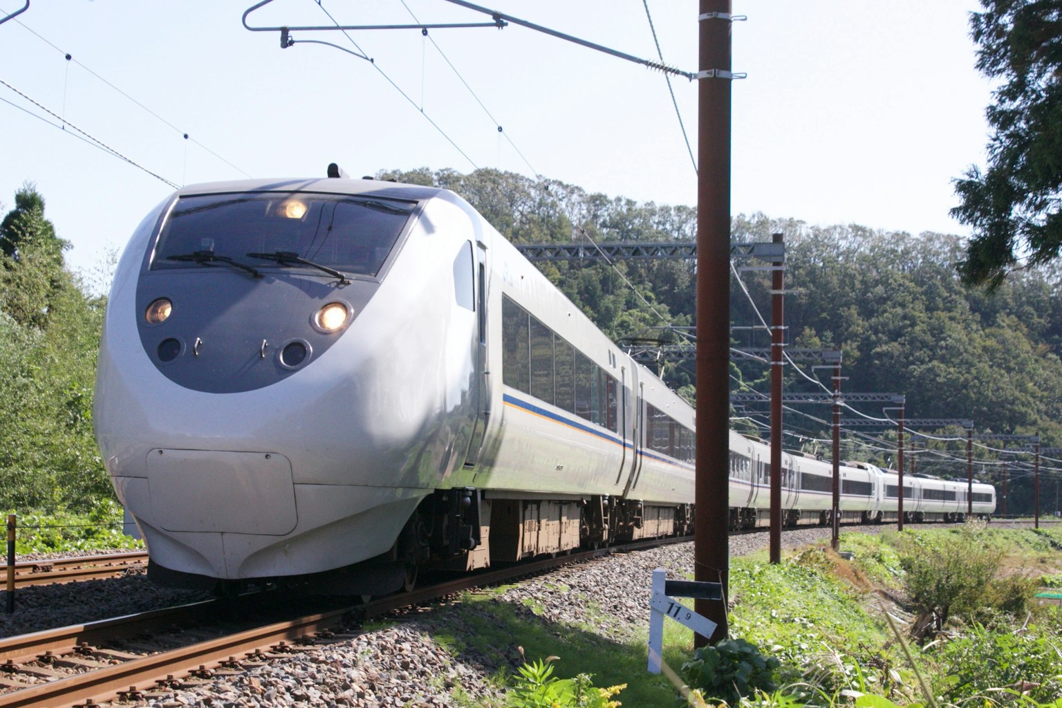White Shinkansen train traveling through green landscape