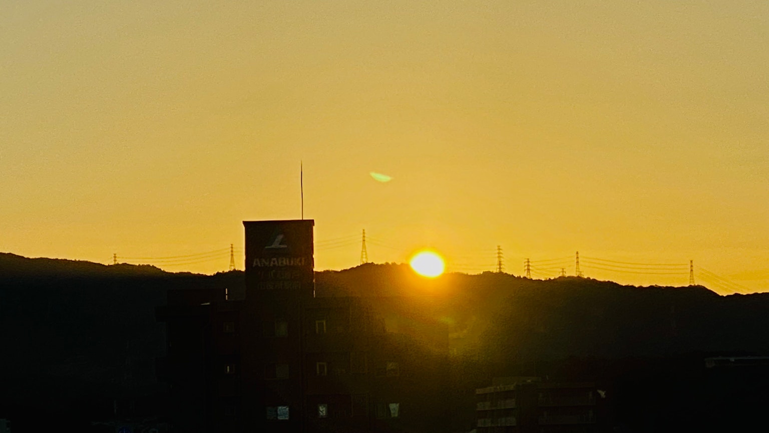 Tramonto dietro le montagne con edifici in silhouette in primo piano