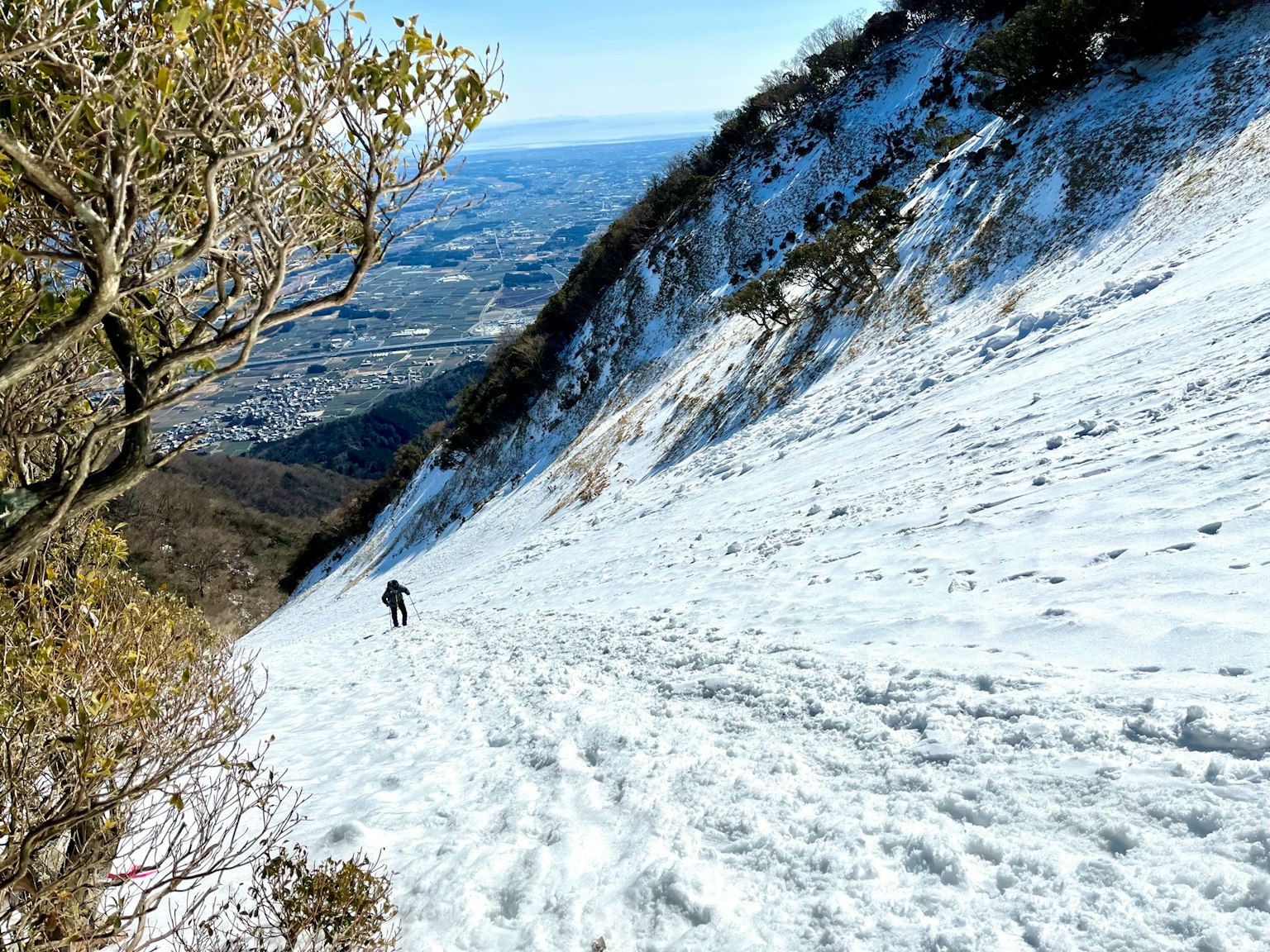 Wanderer, der einen schneebedeckten Hang mit einer malerischen Bergansicht erklimmt