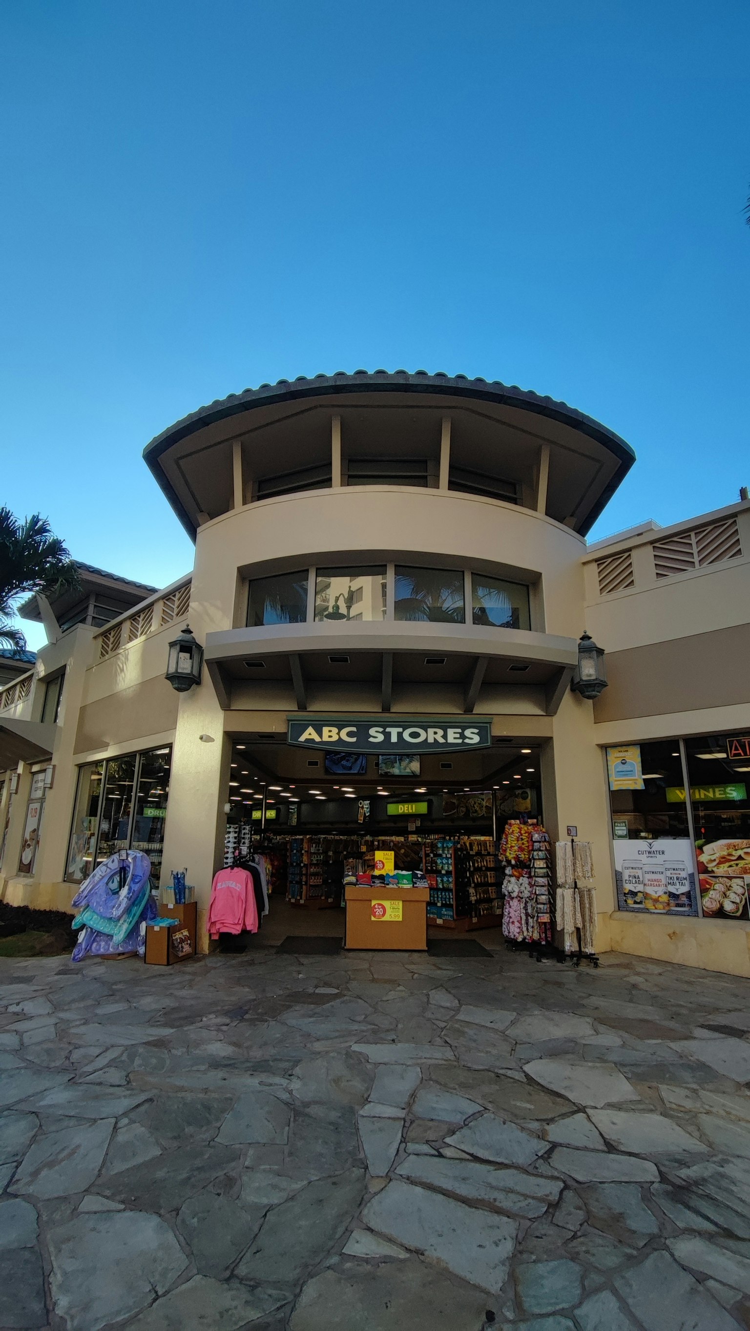 Immagine che mostra l'esterno di ABC Stores con un'insegna luminosa e un ingresso accogliente
