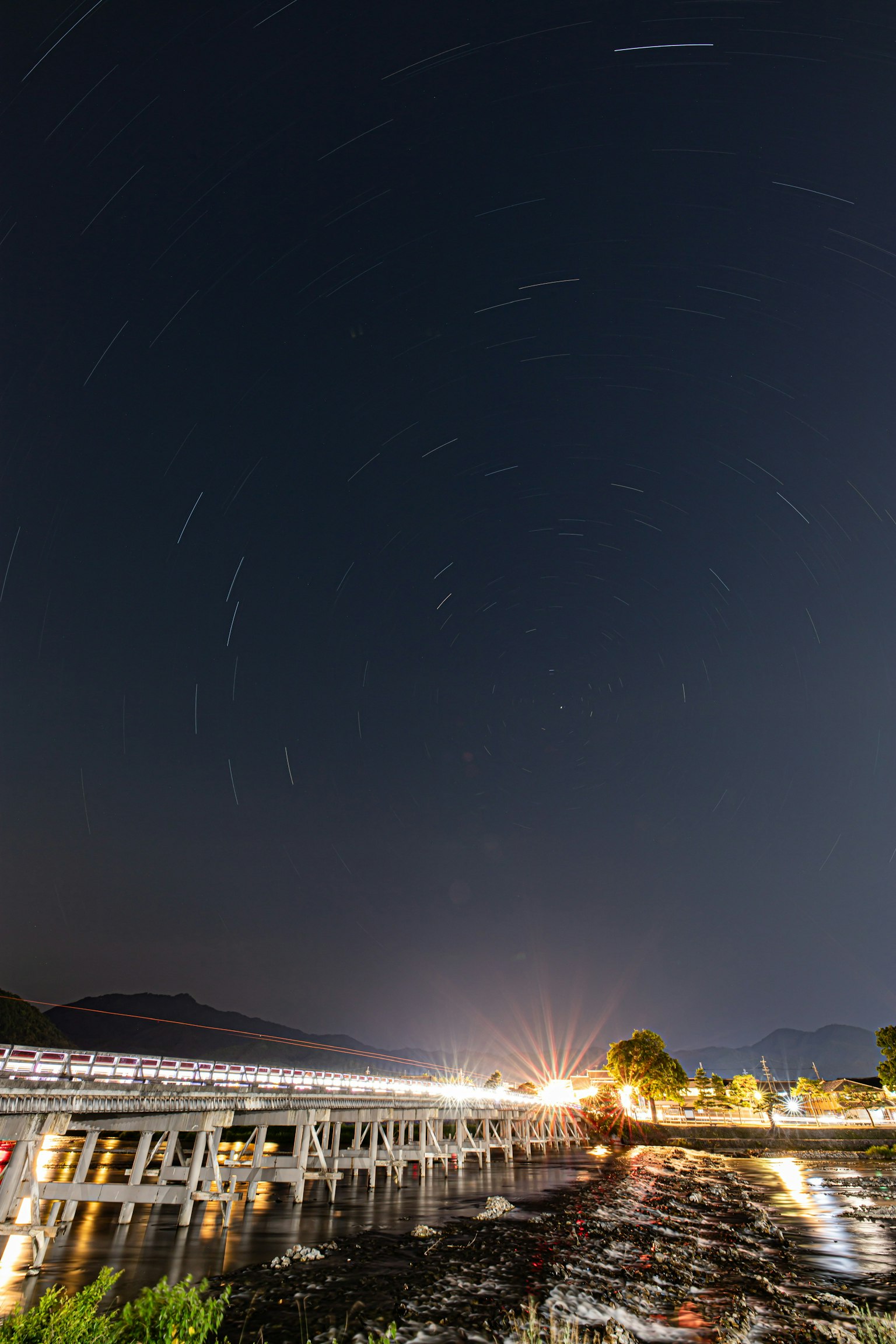 Ciel nocturne avec des traînées d'étoiles et une structure de pont