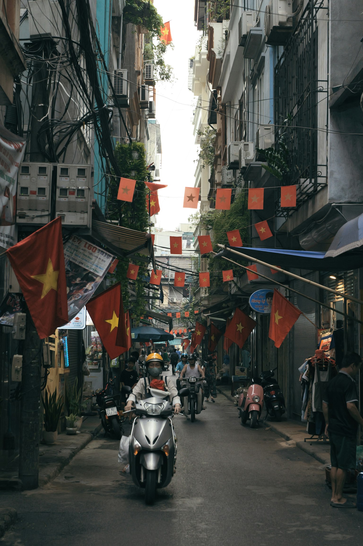 Jalan sempit di Vietnam dihiasi dengan bendera merah dan skuter