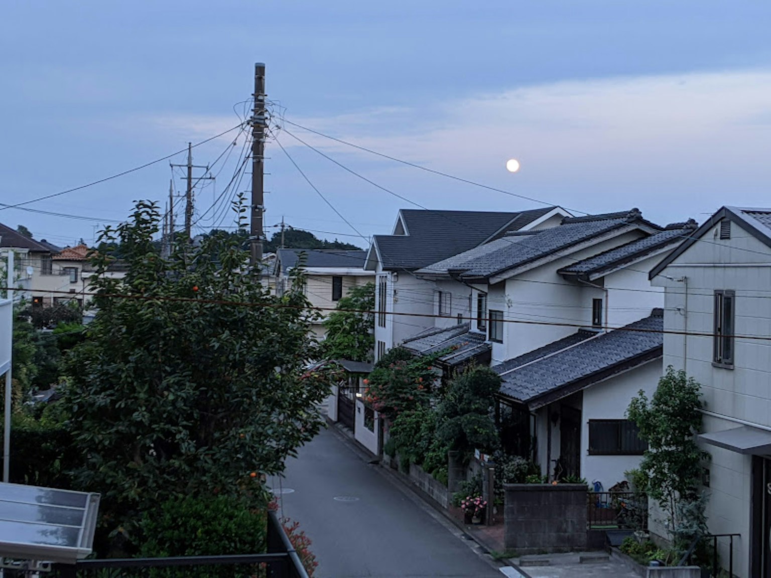 ถนนในเขตที่อยู่อาศัยเงียบสงบในยามพลบค่ำที่มีดวงจันทร์สว่าง