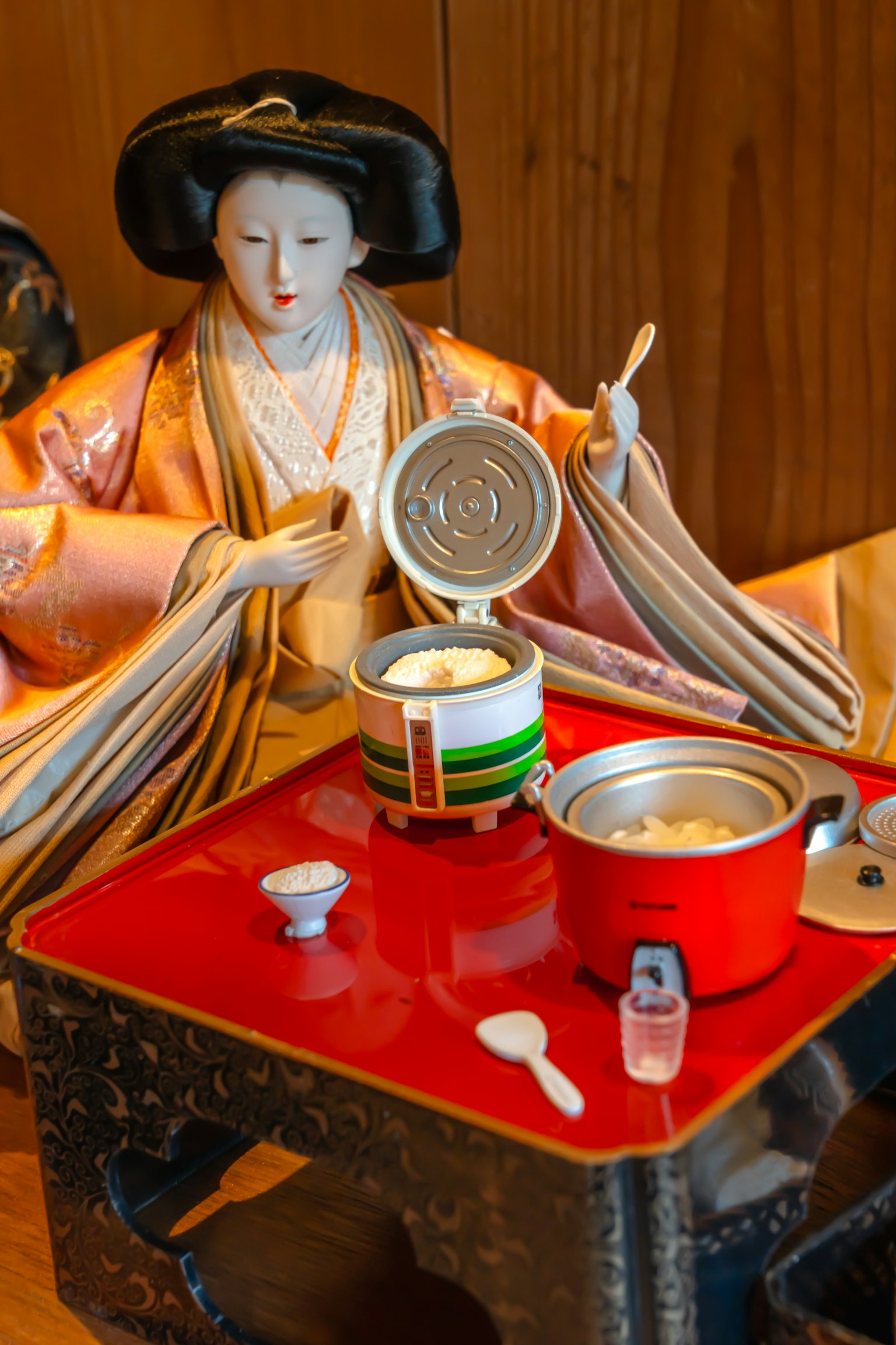 一個穿著傳統服裝的玩偶在紅色桌子上準備食物