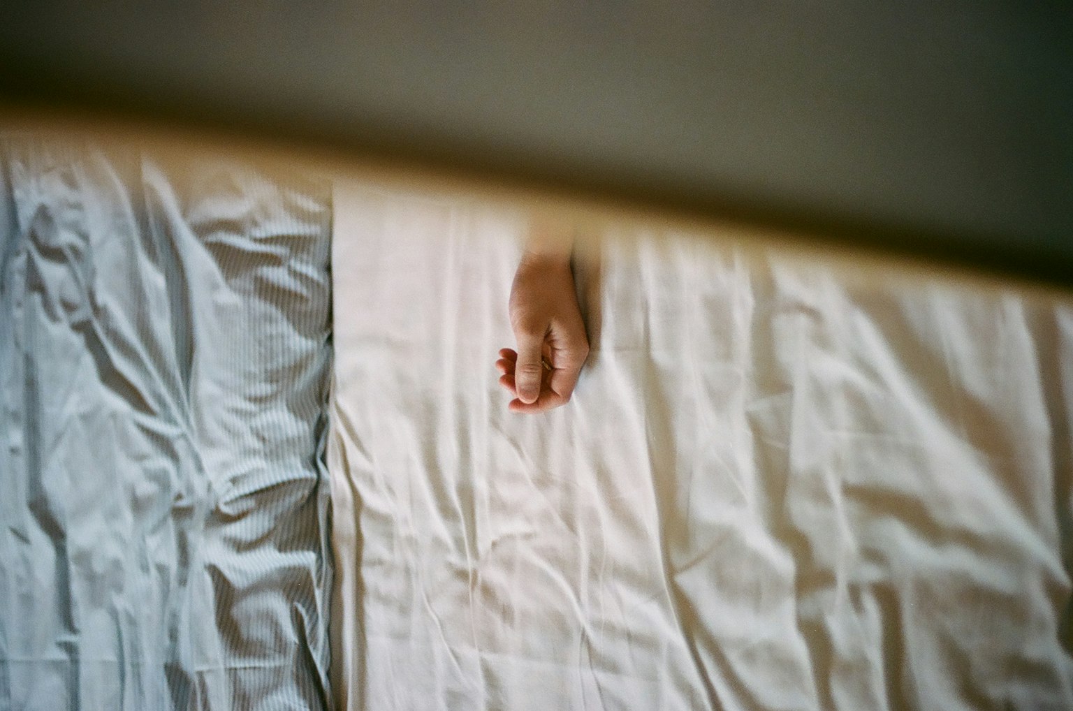 Gros plan d'une main reposant sur des draps blancs