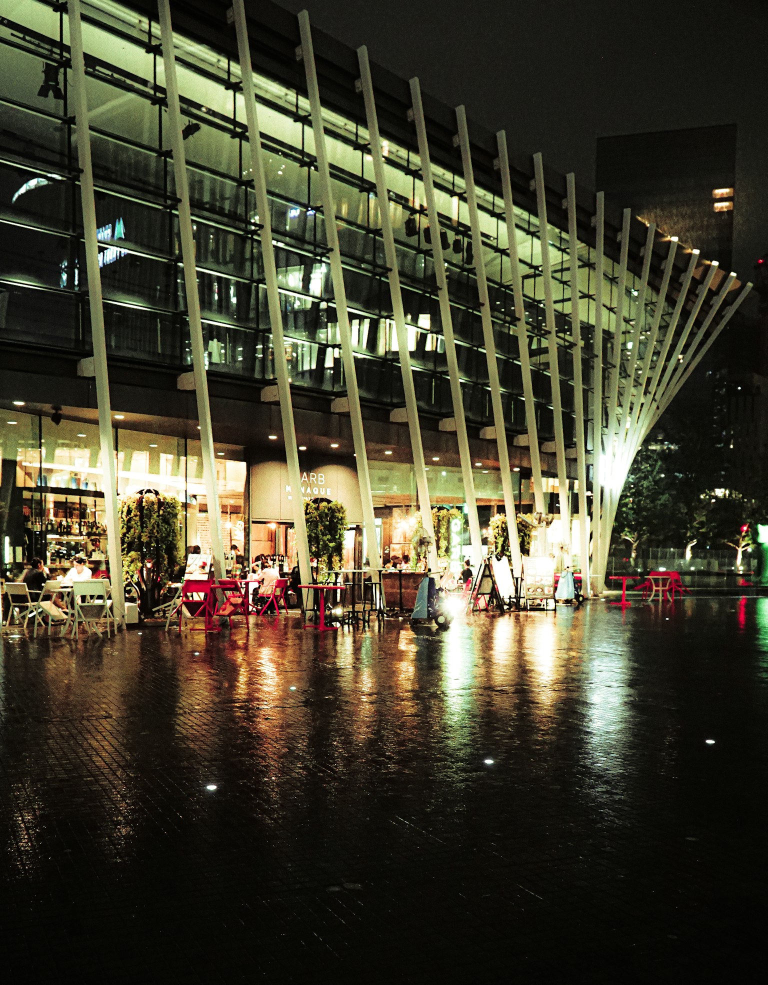 Edificio arquitectónico moderno de noche con reflejos en el pavimento mojado