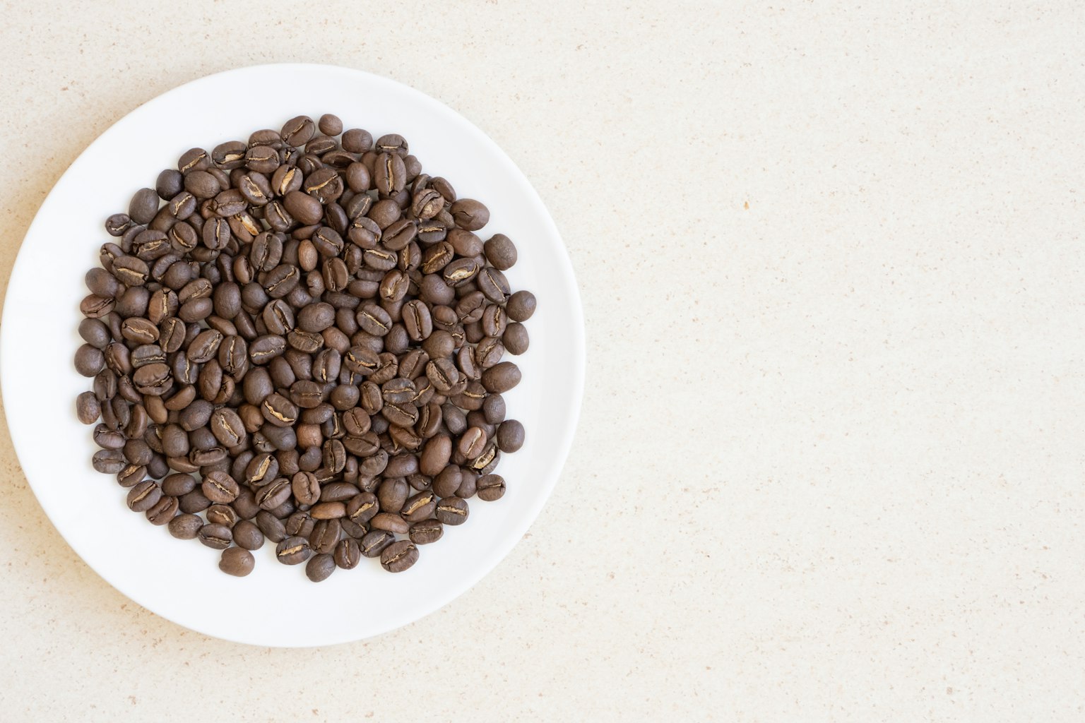 Close-up biji kopi panggang di atas piring putih