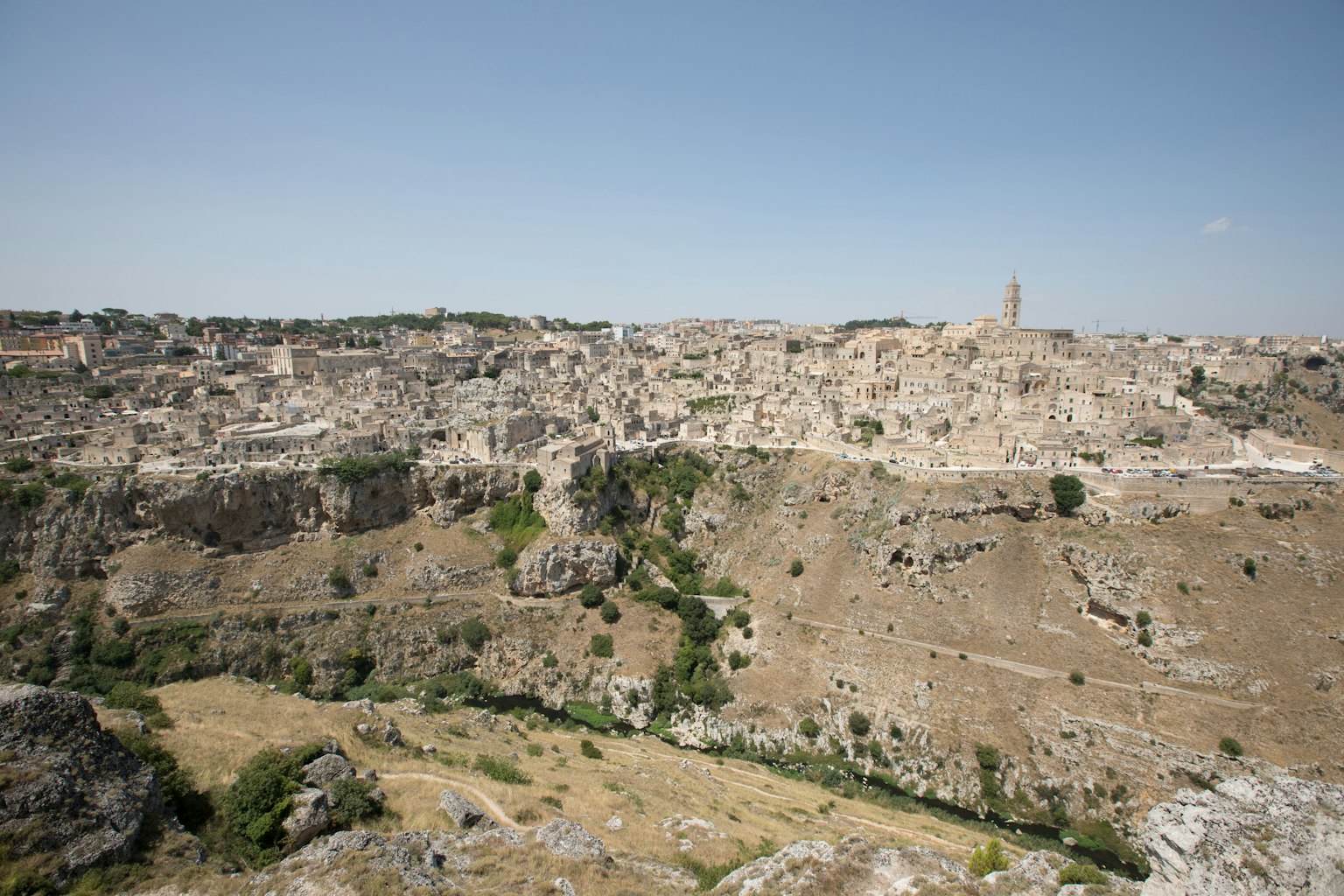 Vista panorámica de Matera que muestra edificios de piedra y terreno rocoso