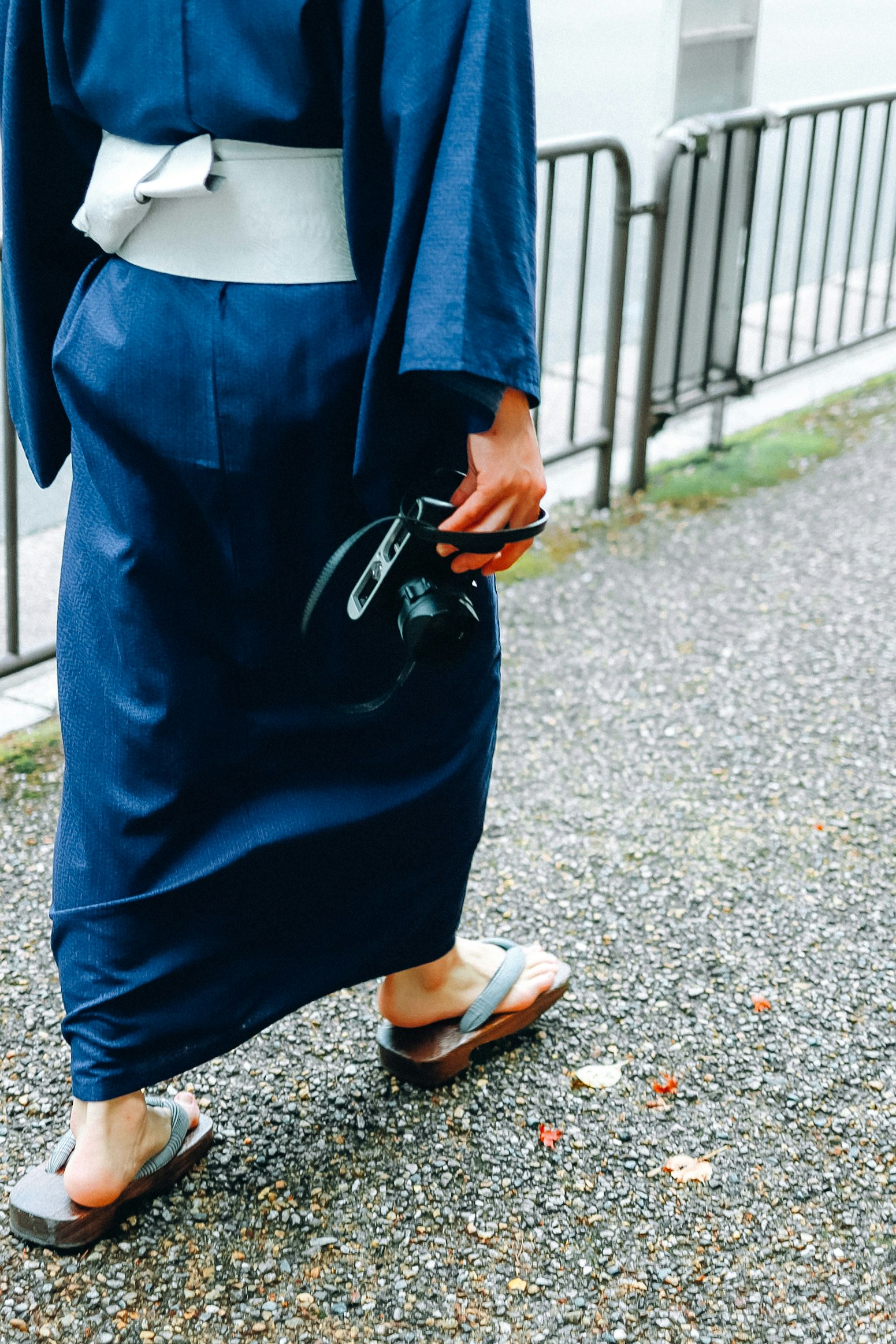 Un passage extérieur où une personne en tenue de travail bleue marche en tenant des outils