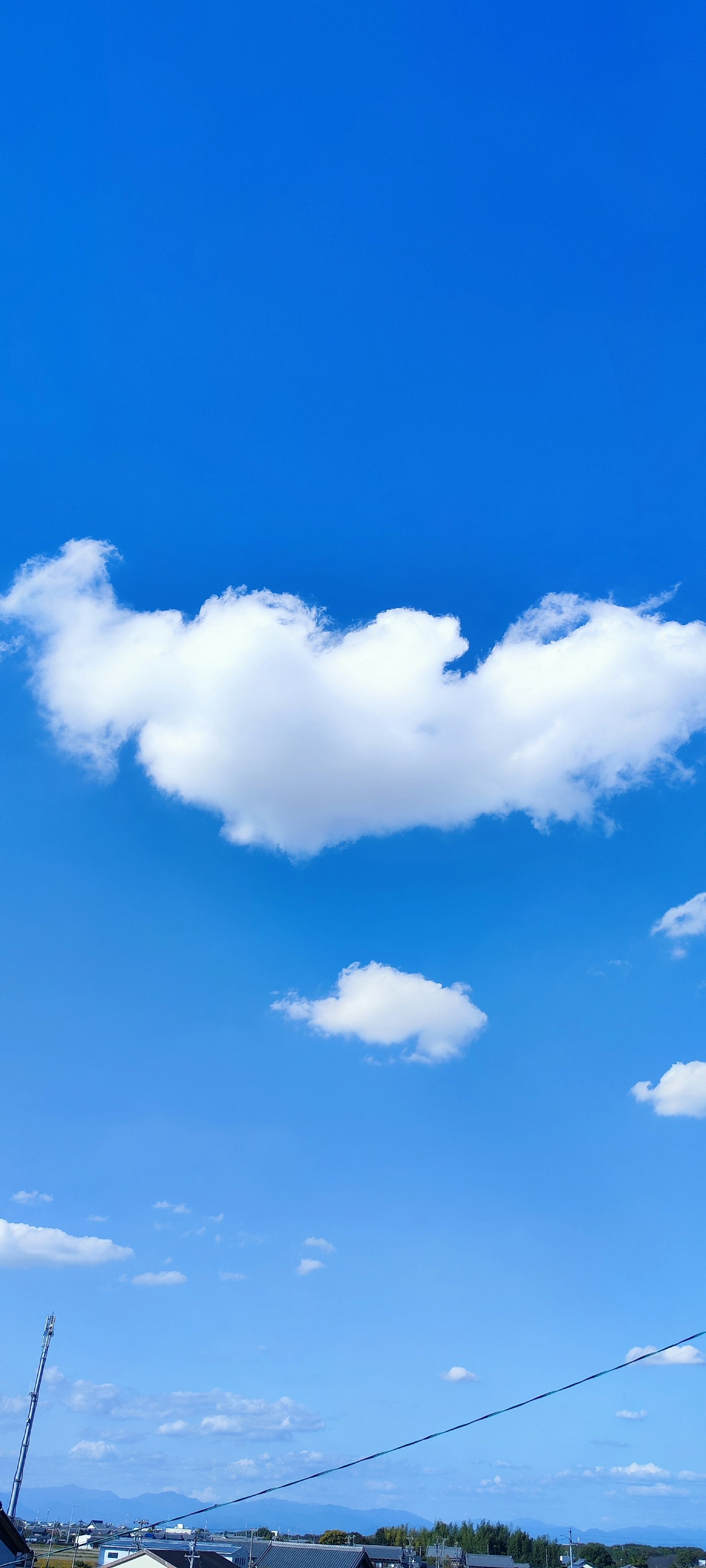 Nube en forma de corazón en un cielo azul con pequeñas nubes blancas