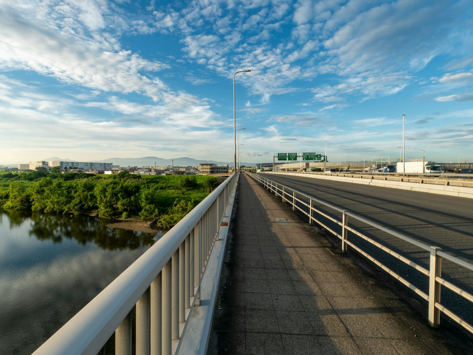 Ampio ponte con cielo blu e vegetazione verde accanto all'acqua