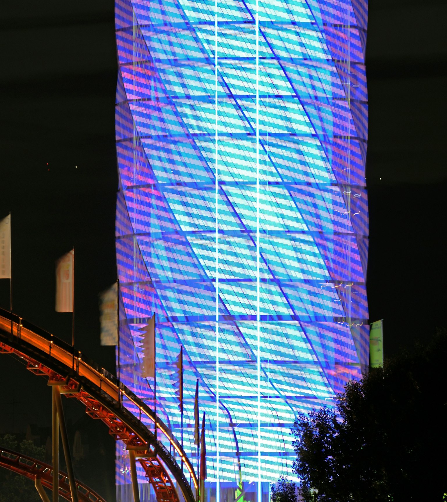 夜间用蓝光装饰的高层建筑与过山车