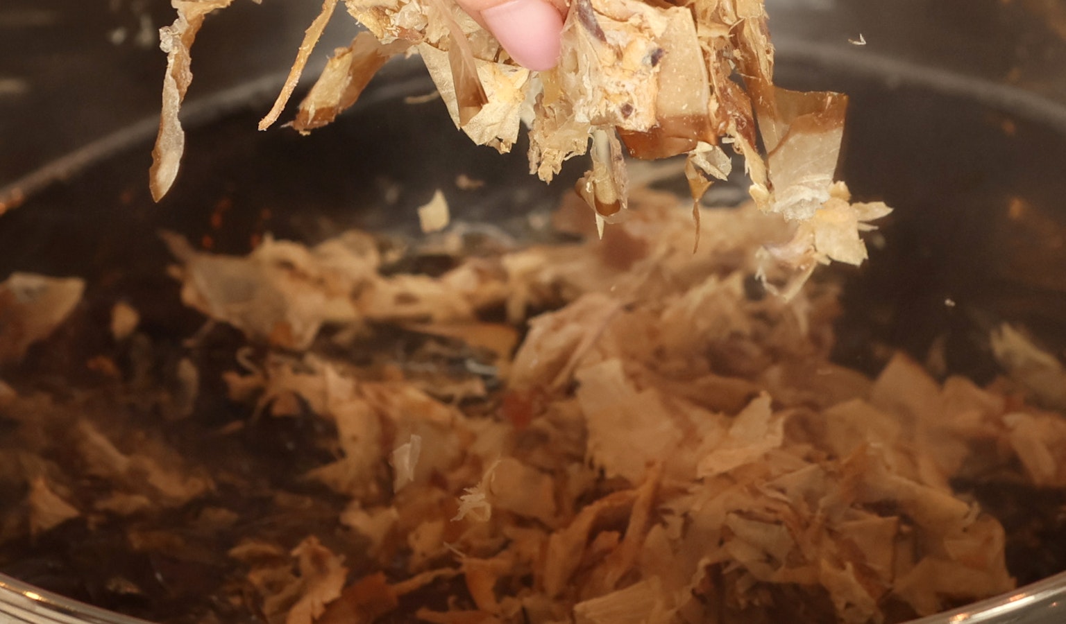 Main tenant de la viande effilochée au-dessus d'une casserole