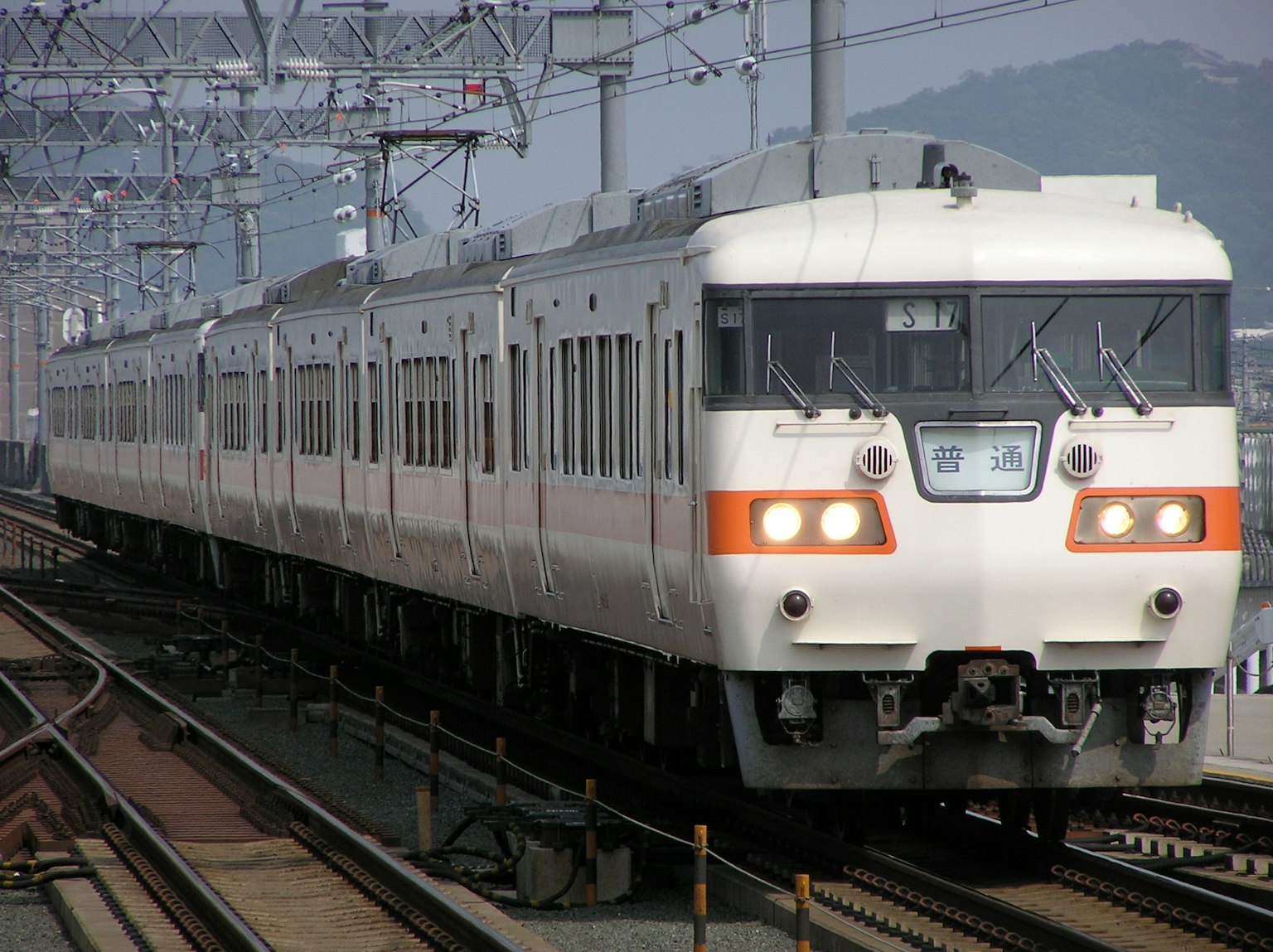 Un tren blanco y naranja que circula por las vías