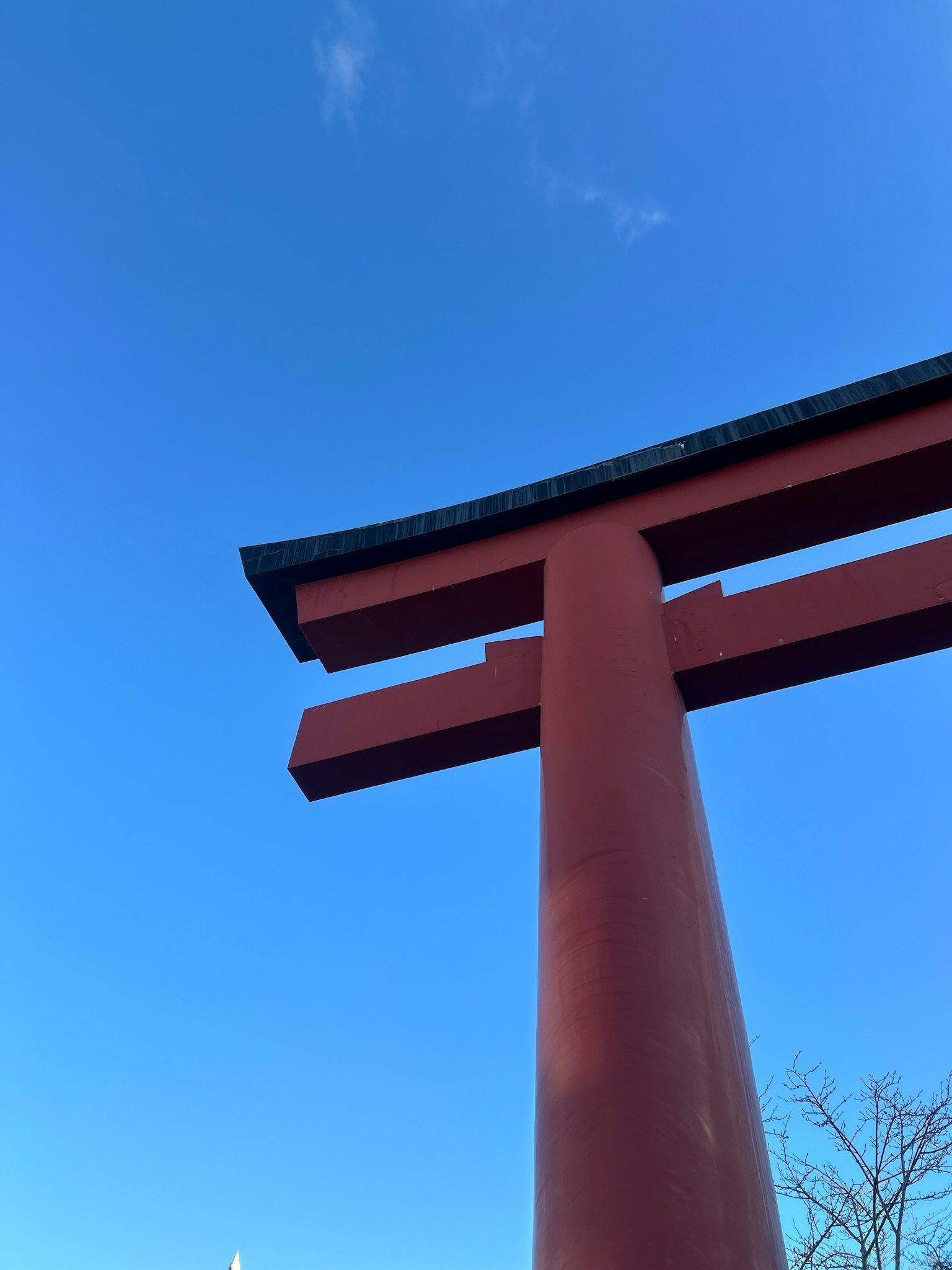 Part of a red torii gate under a blue sky