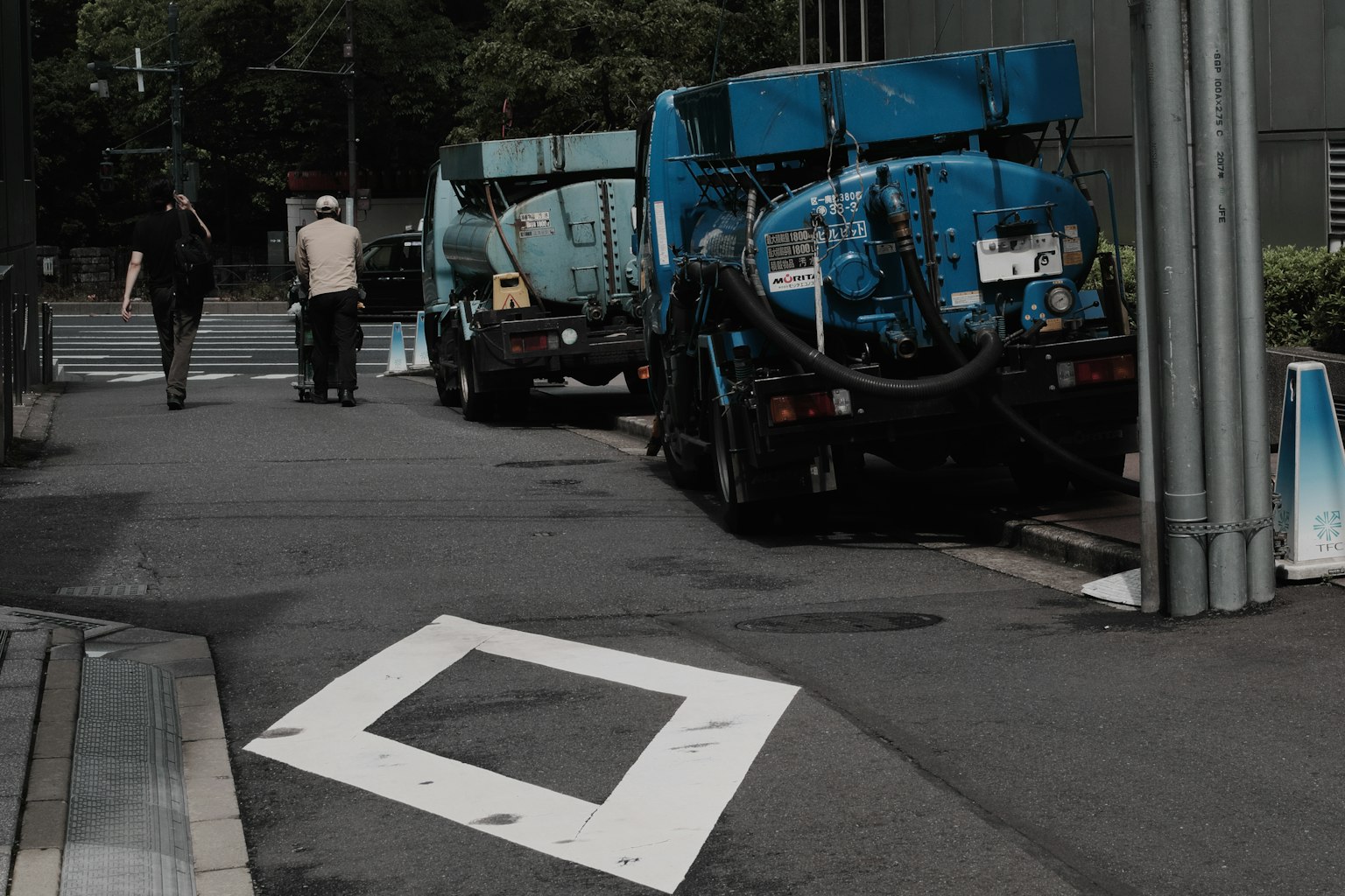 Street scene with blue trucks parked and a pedestrian