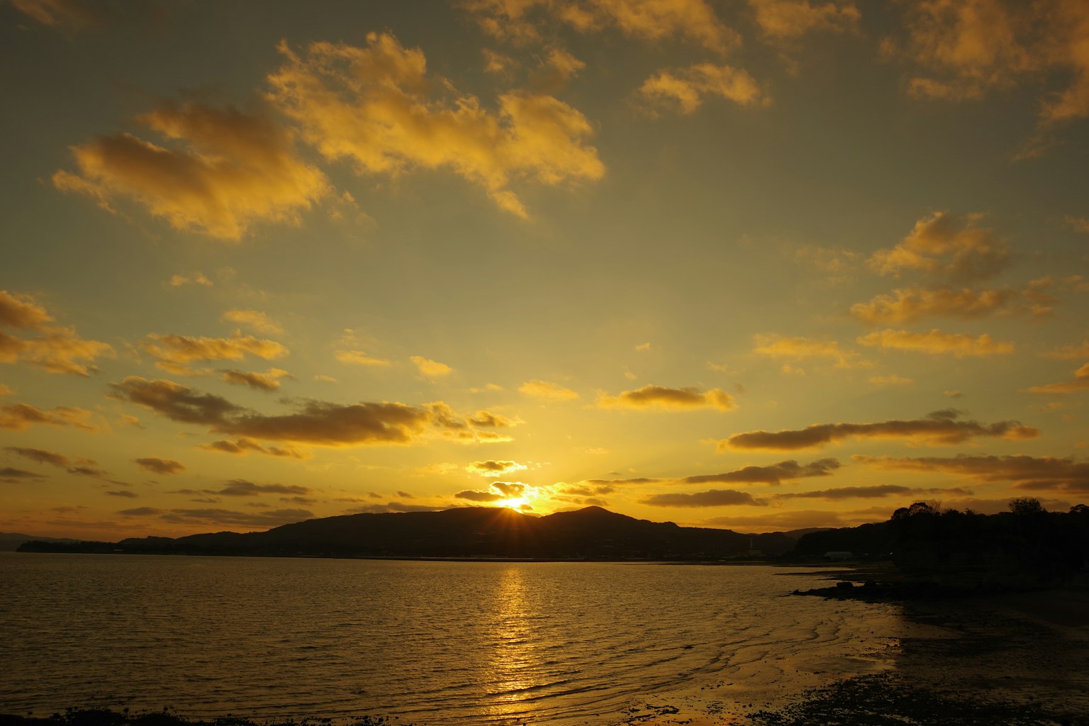 Beautiful landscape with sunset behind mountains reflecting on the water