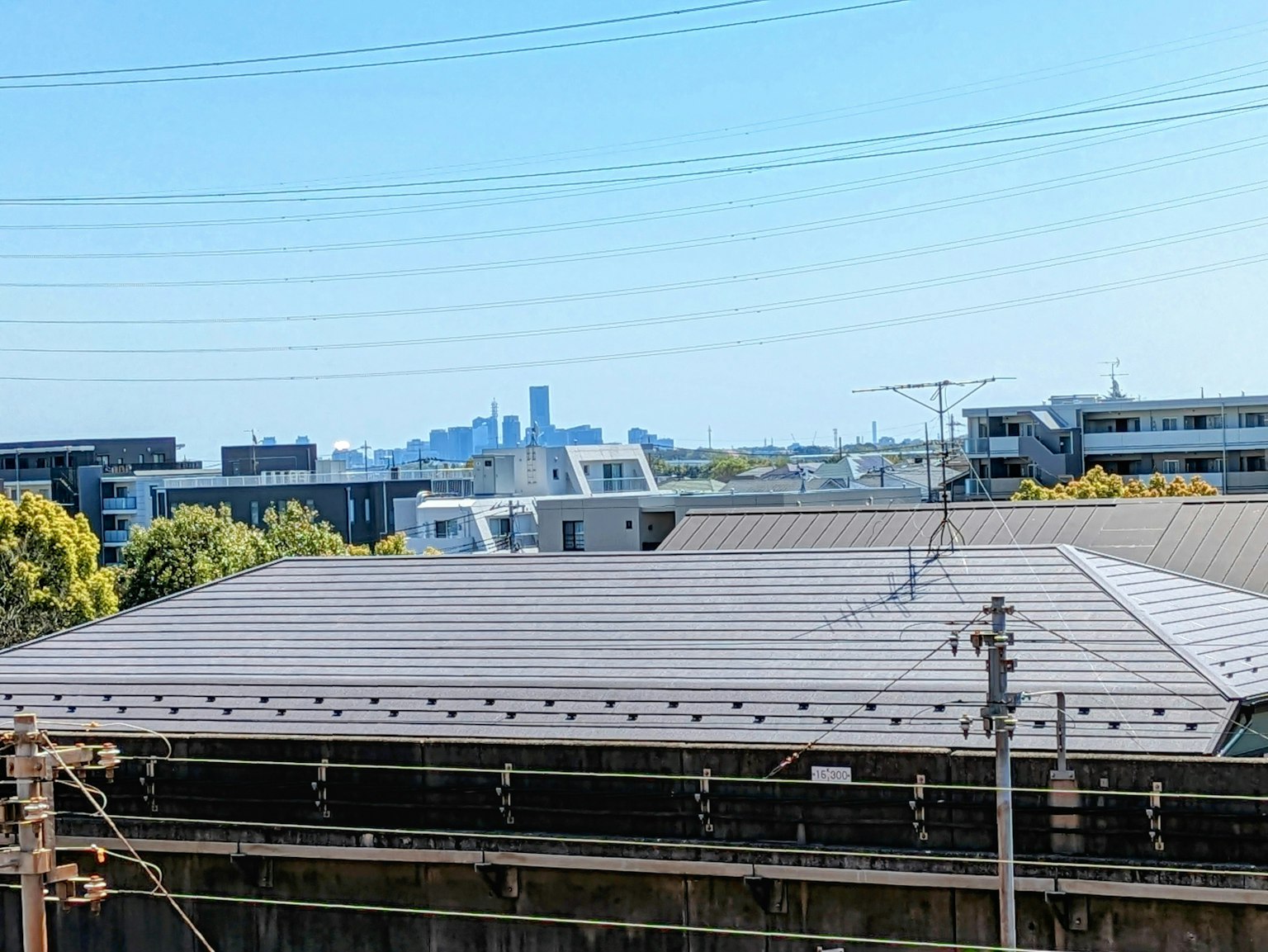 Toit avec des lignes électriques devant une skyline urbaine