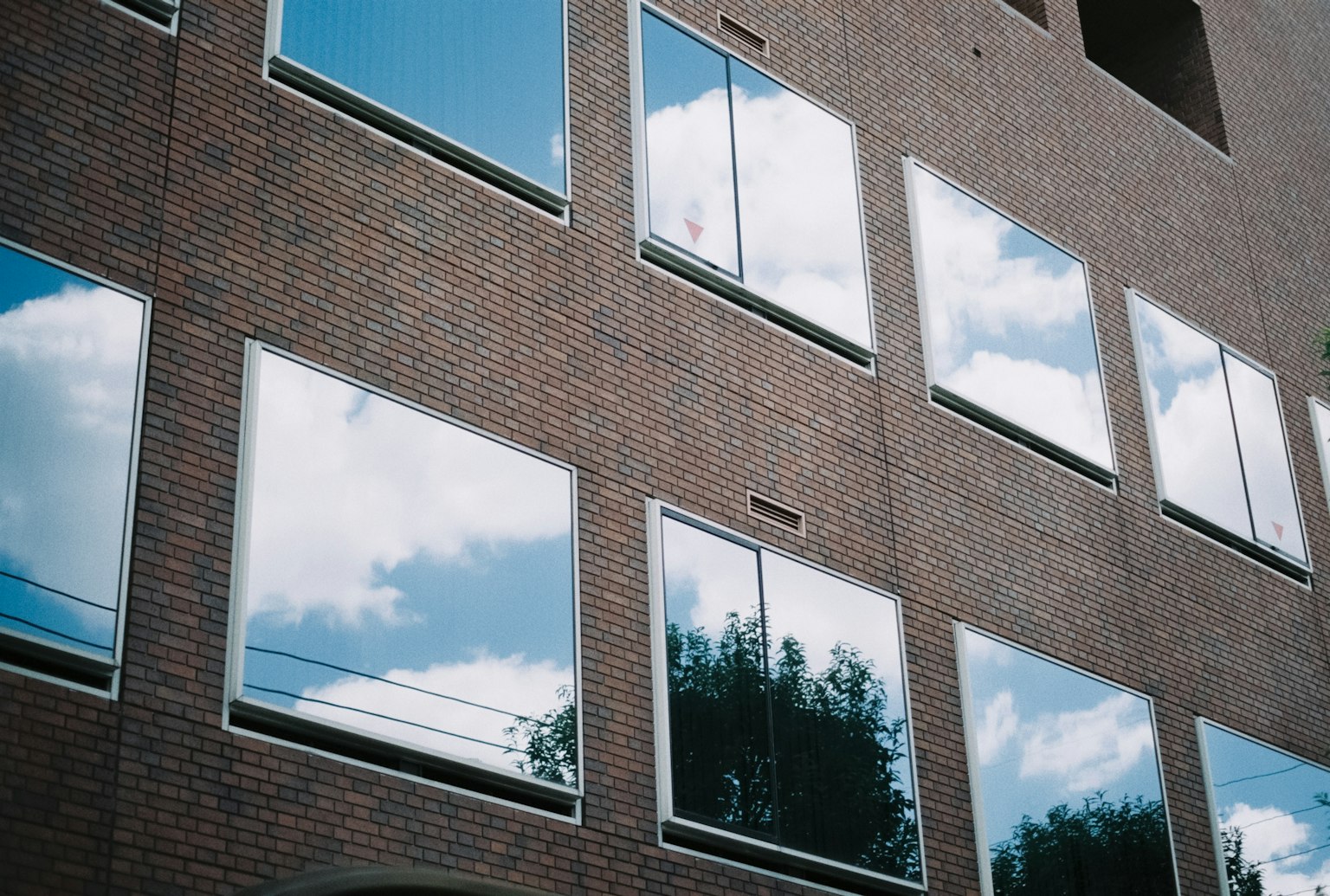 Reflets de nuages et d'arbres dans des fenêtres sur un mur en briques