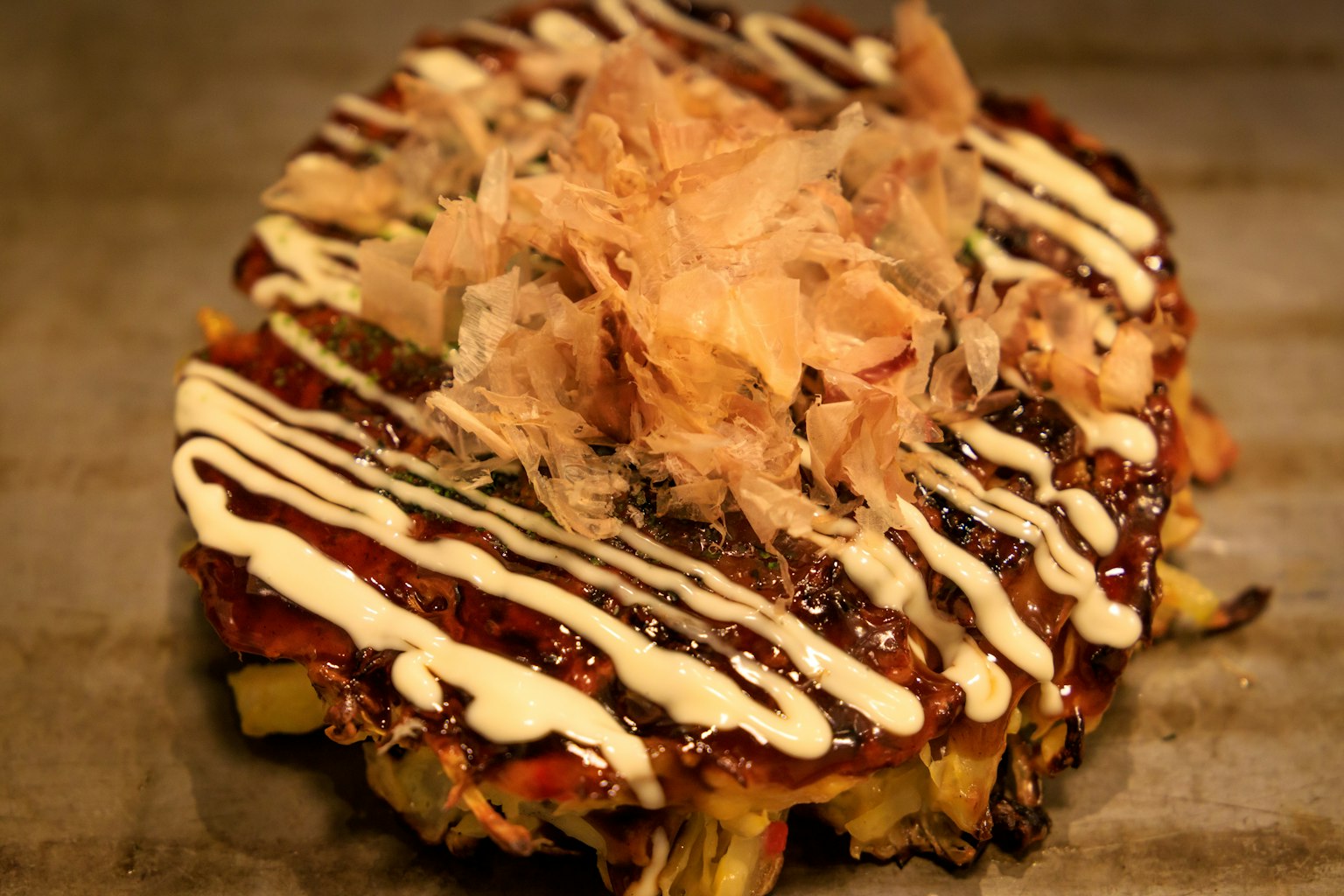 Okonomiyaki cubierto con copos de bonito y salsa