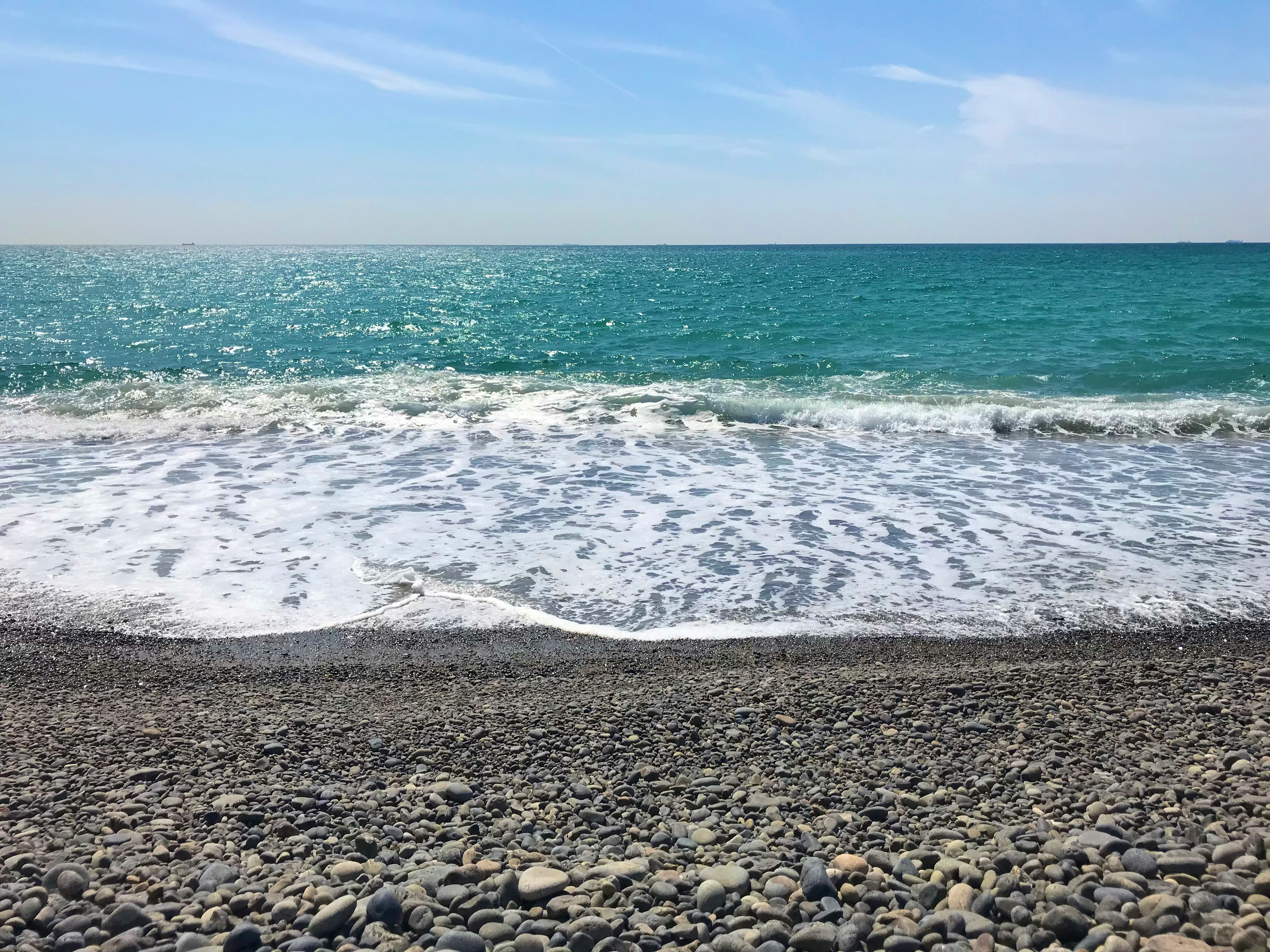 Pebble beach with waves rolling in under a blue sky