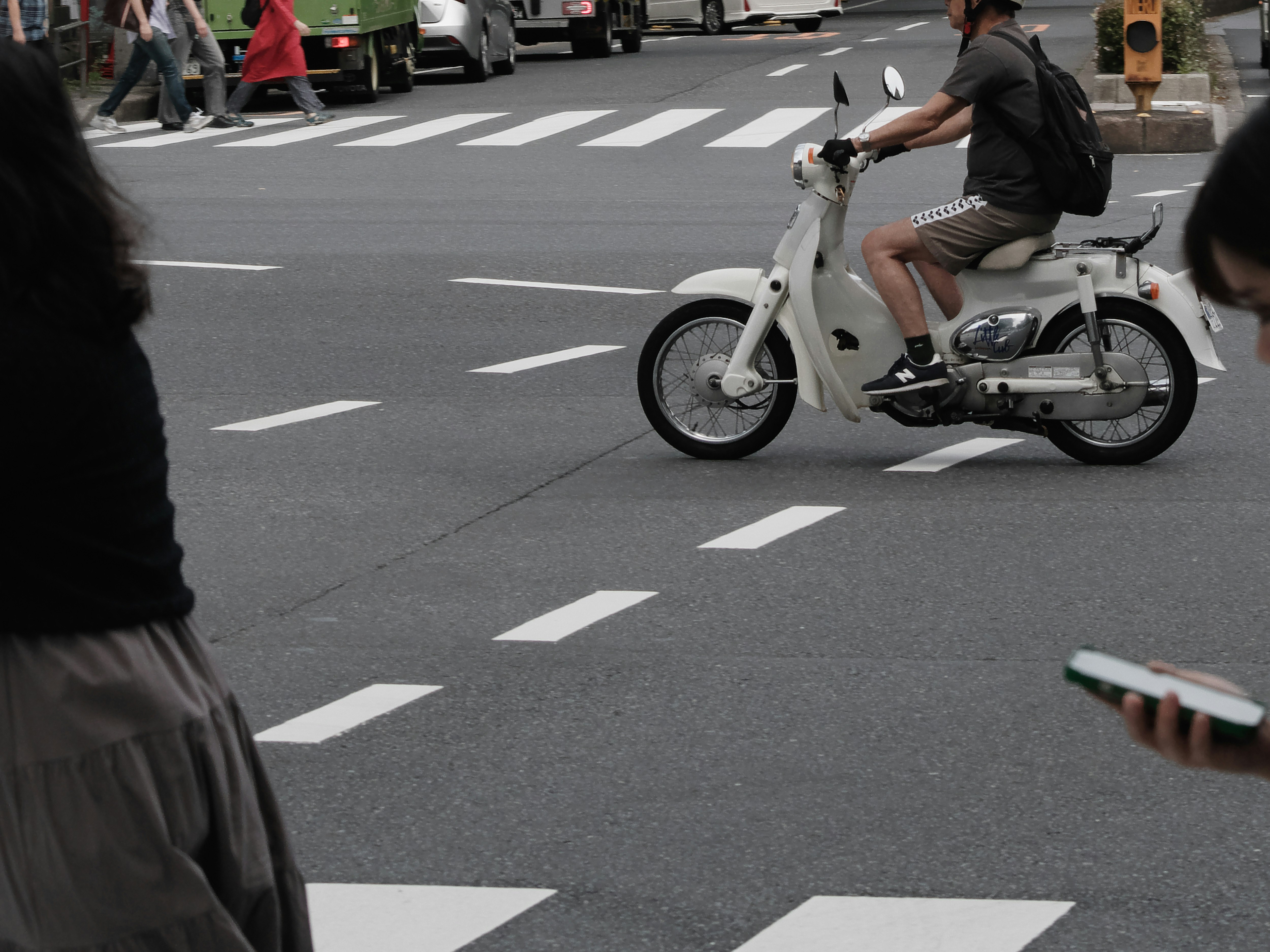 scooter roulant à un carrefour avec des piétons dans une rue urbaine