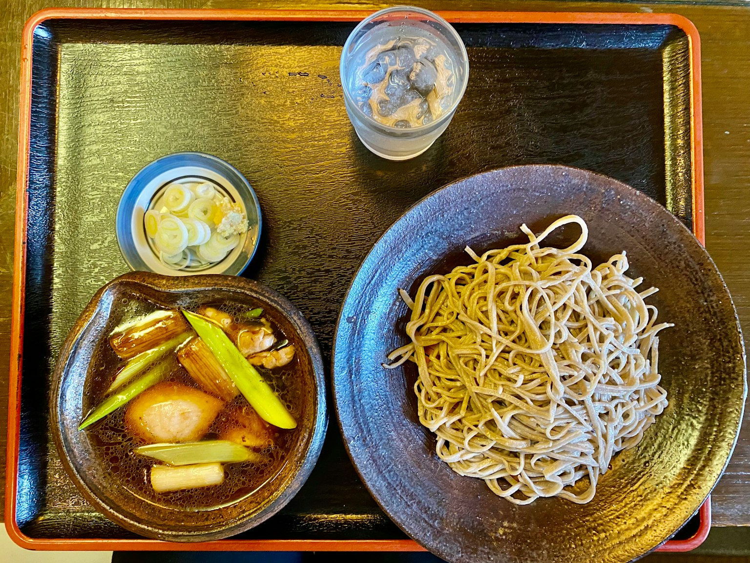 Un pasto con noodles soba, salsa di immersione e un contorno di sottaceti