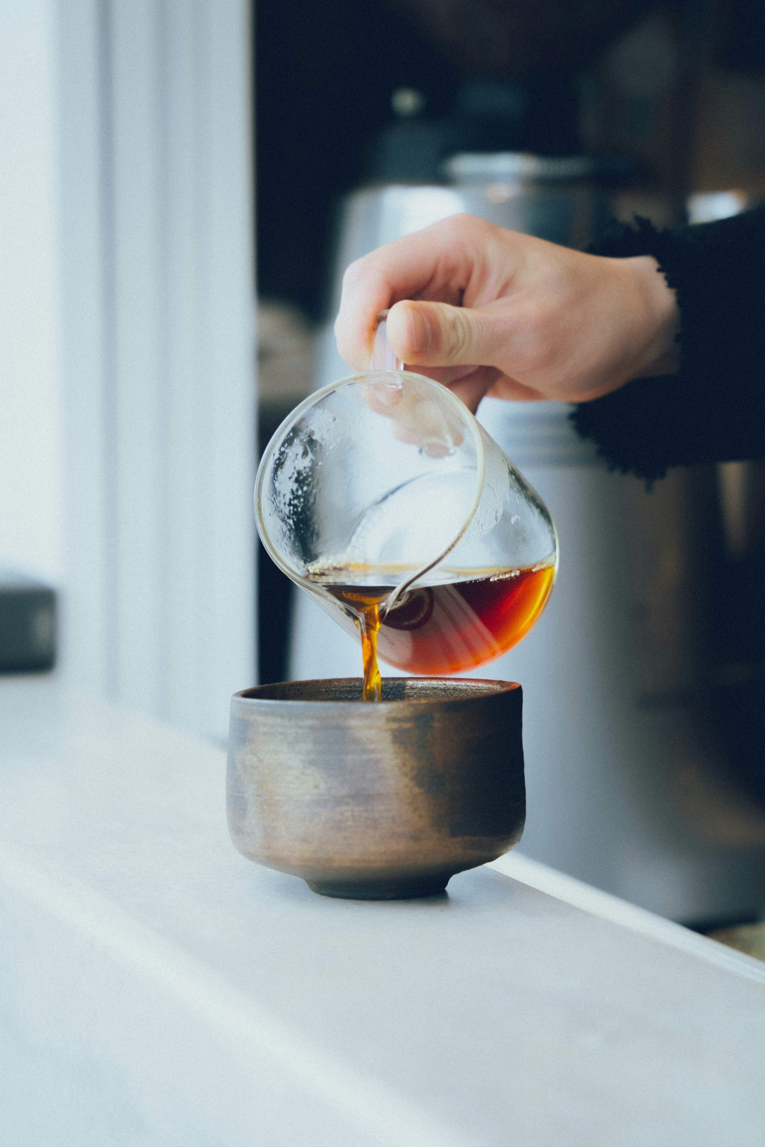 手将茶水倒入冒着热气的杯中