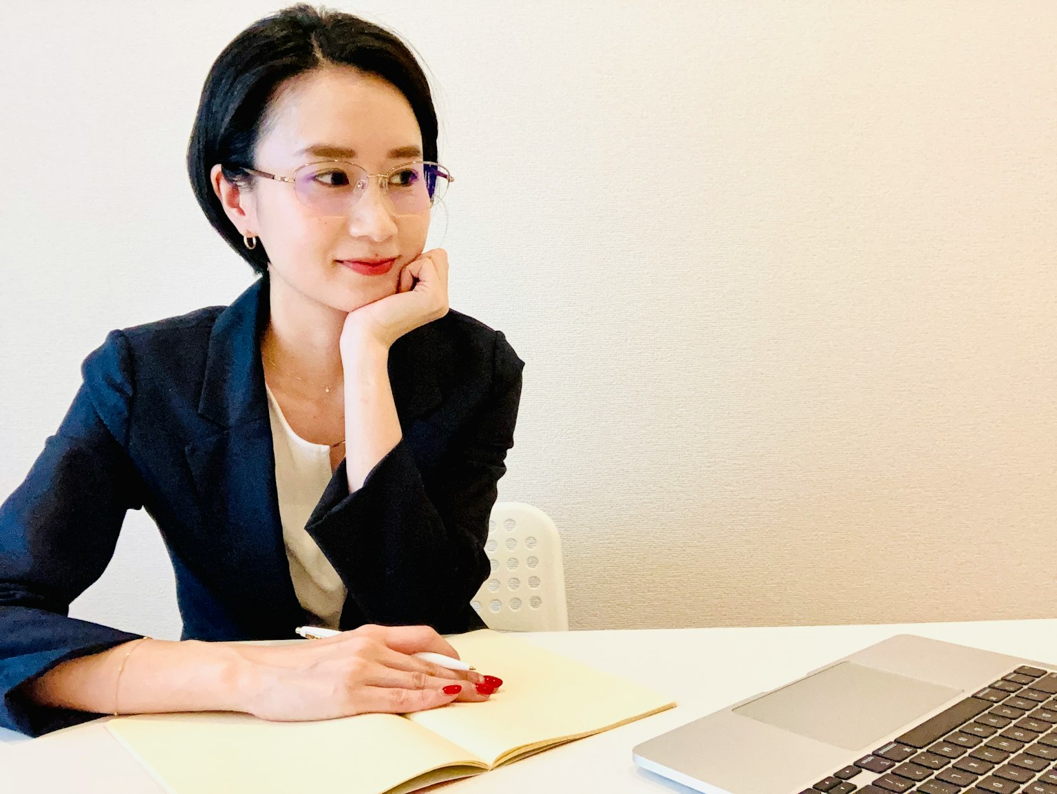 Một người phụ nữ mặc vest ngồi suy tư nhìn vào laptop