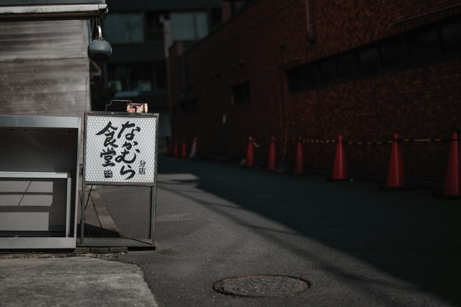 Narrow alley featuring a restaurant sign and red traffic cones