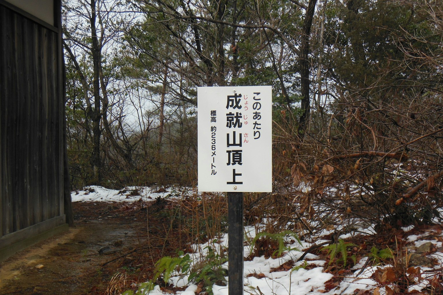 Panneau indiquant le sommet de Naritōzan avec un paysage enneigé