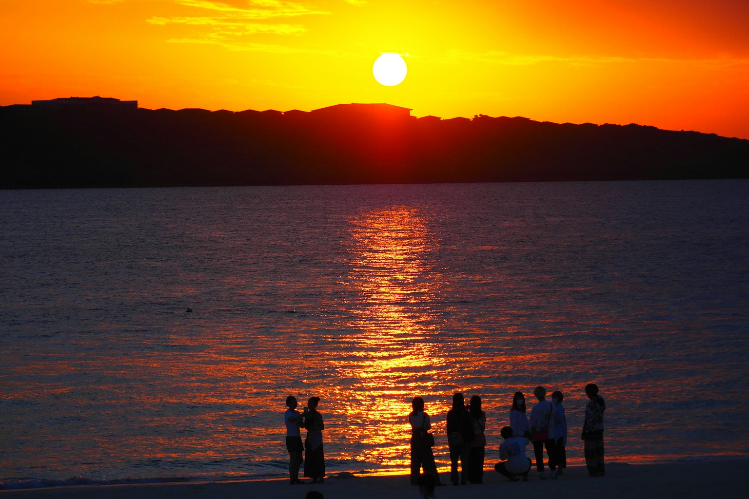 Personas reunidas en la playa al atardecer