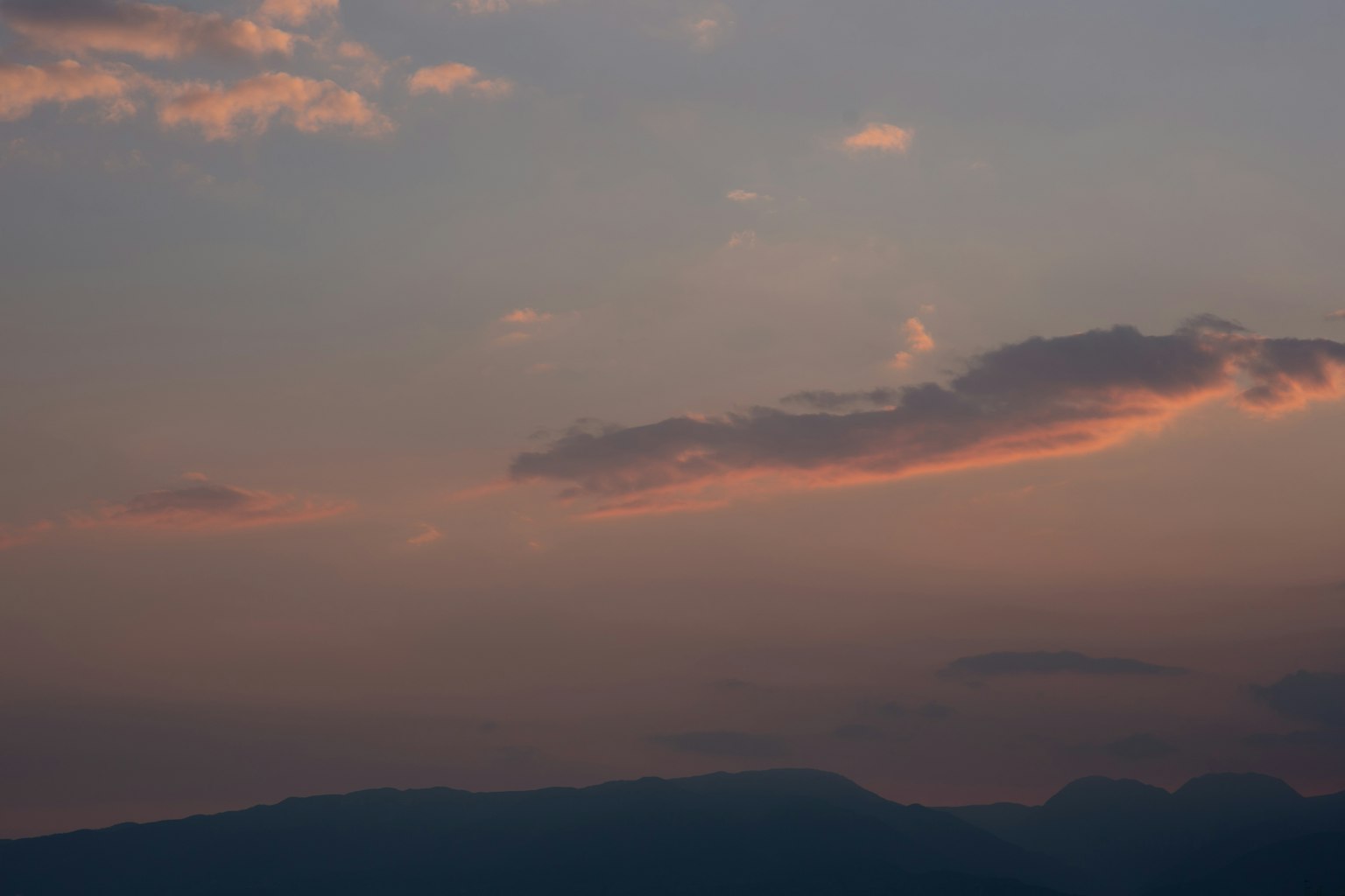 Silueta de montañas bajo un cielo al atardecer con nubes