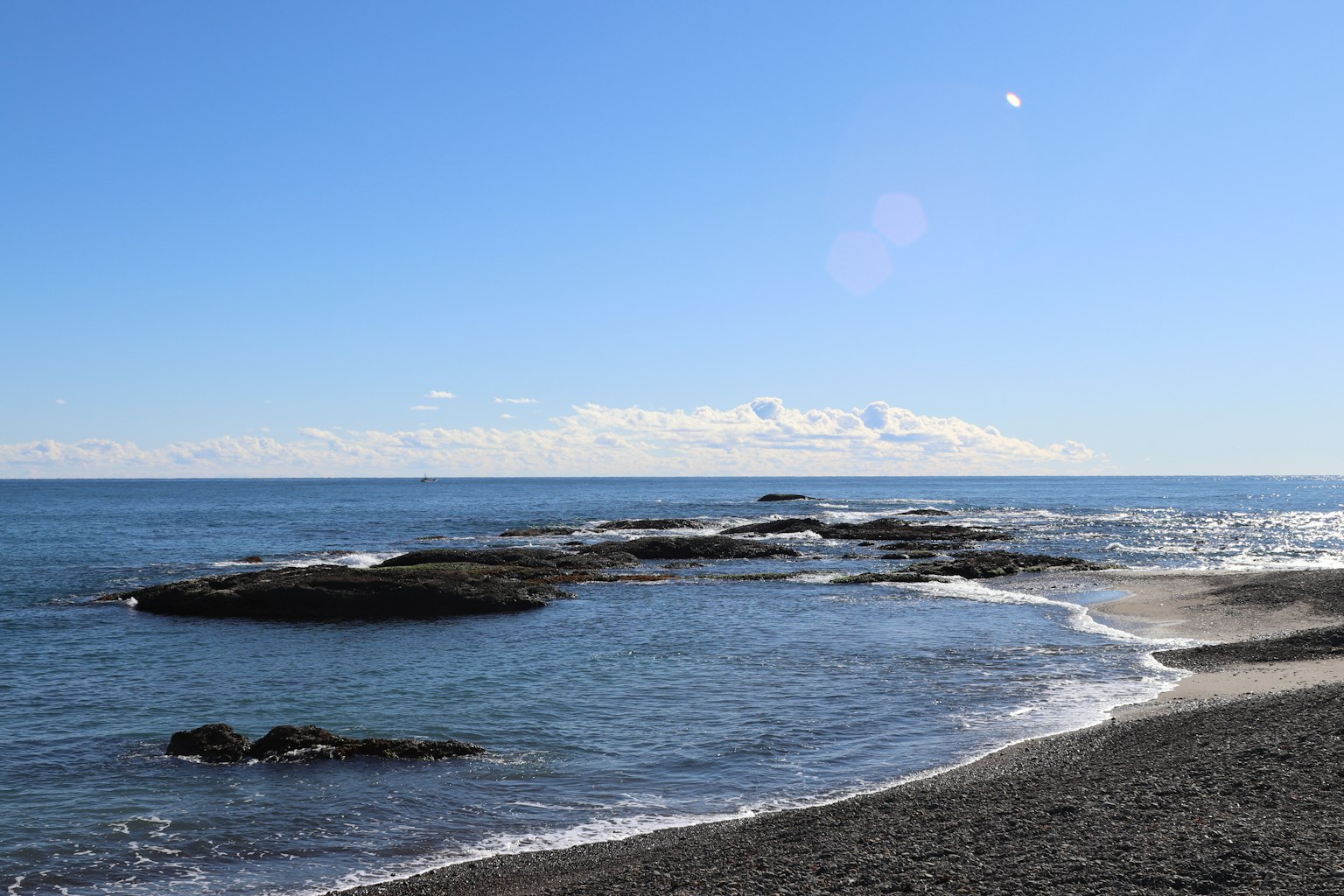 蓝天和海洋的美丽景色，沙滩上的岩石和海浪