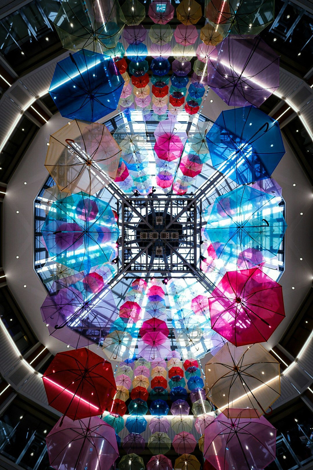 Bunte Regenschirme hängen von der Decke gesehen von unten Helle Beleuchtung und Glasstruktur sind vorhanden