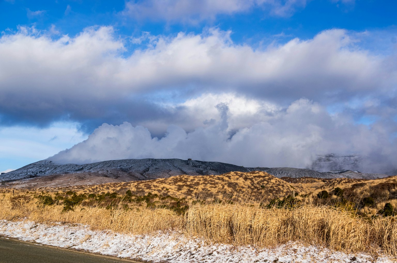 Paisaje montañoso con cielo azul y nubes blancas pradera seca en primer plano