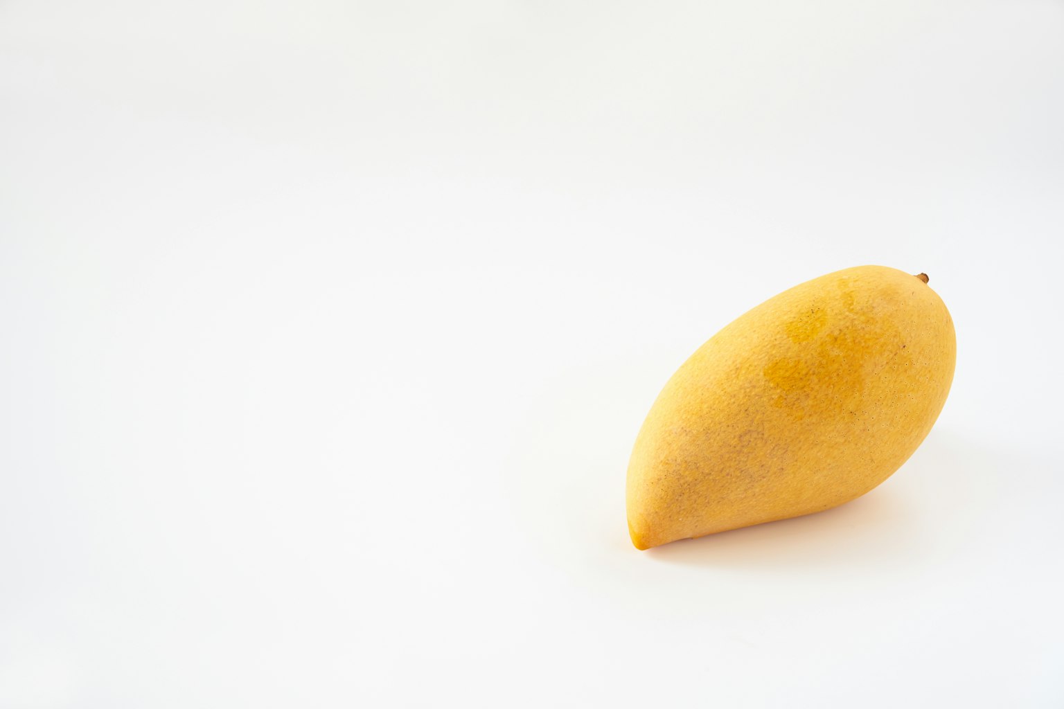Un mango giallo su uno sfondo bianco semplice