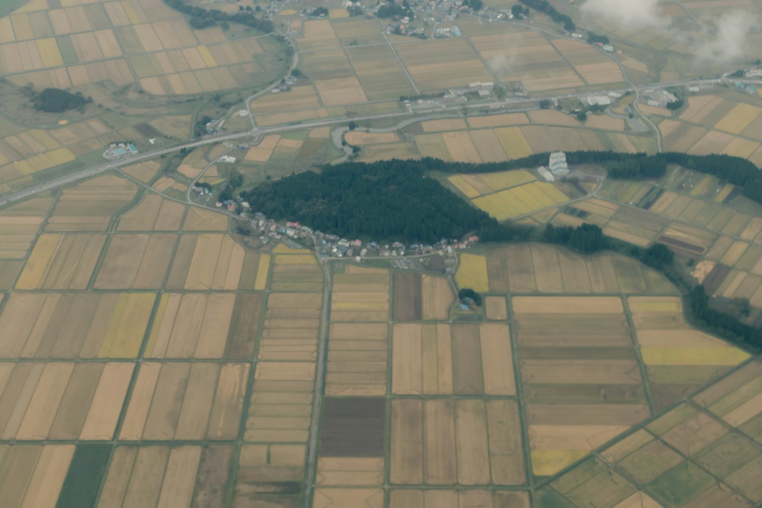Vue aérienne d'un paysage agricole avec des champs colorés et un petit village