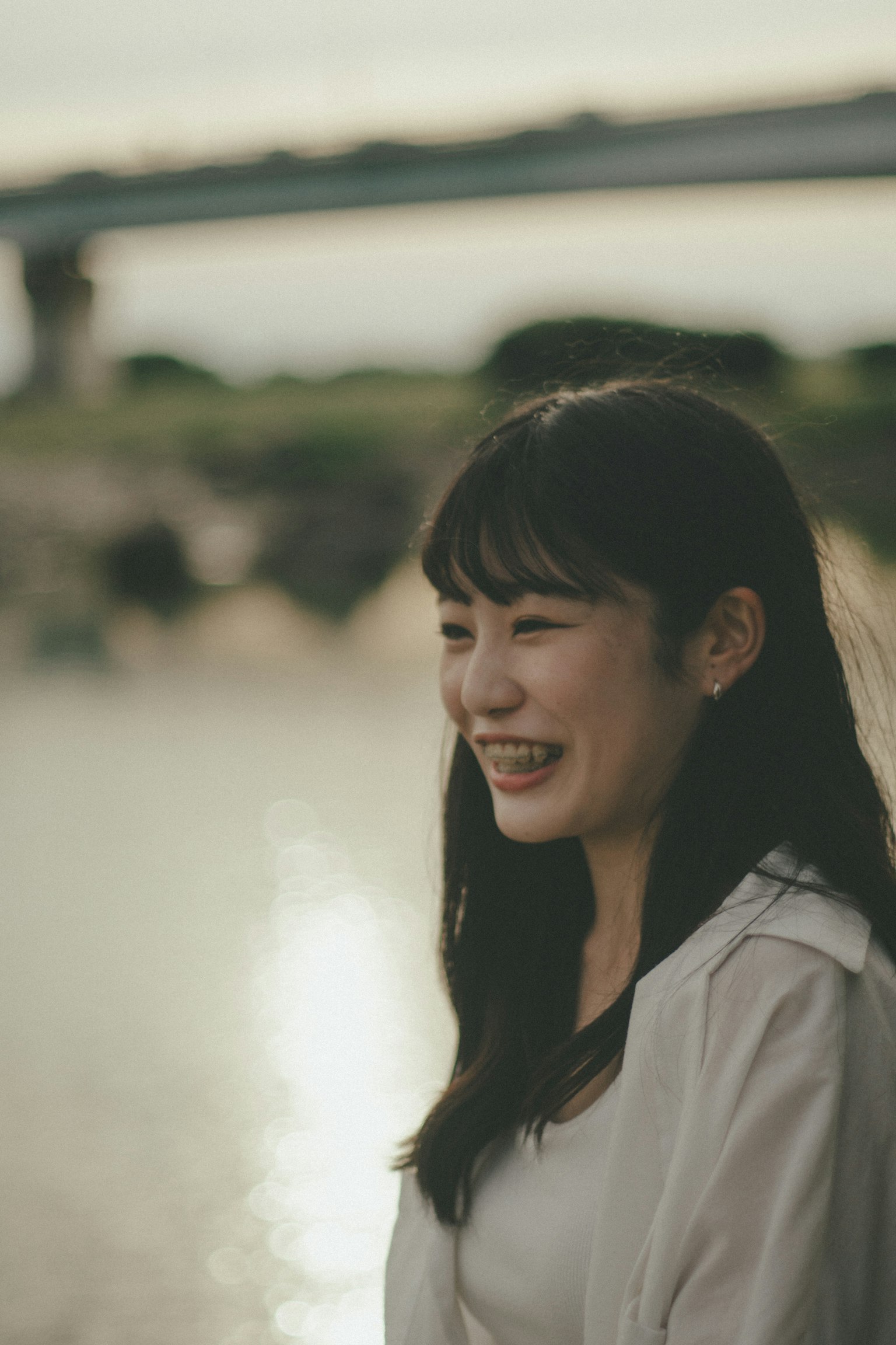 강가에서 미소 짓고 있는 여성의 초상 배경에 다리와 부드러운 조명