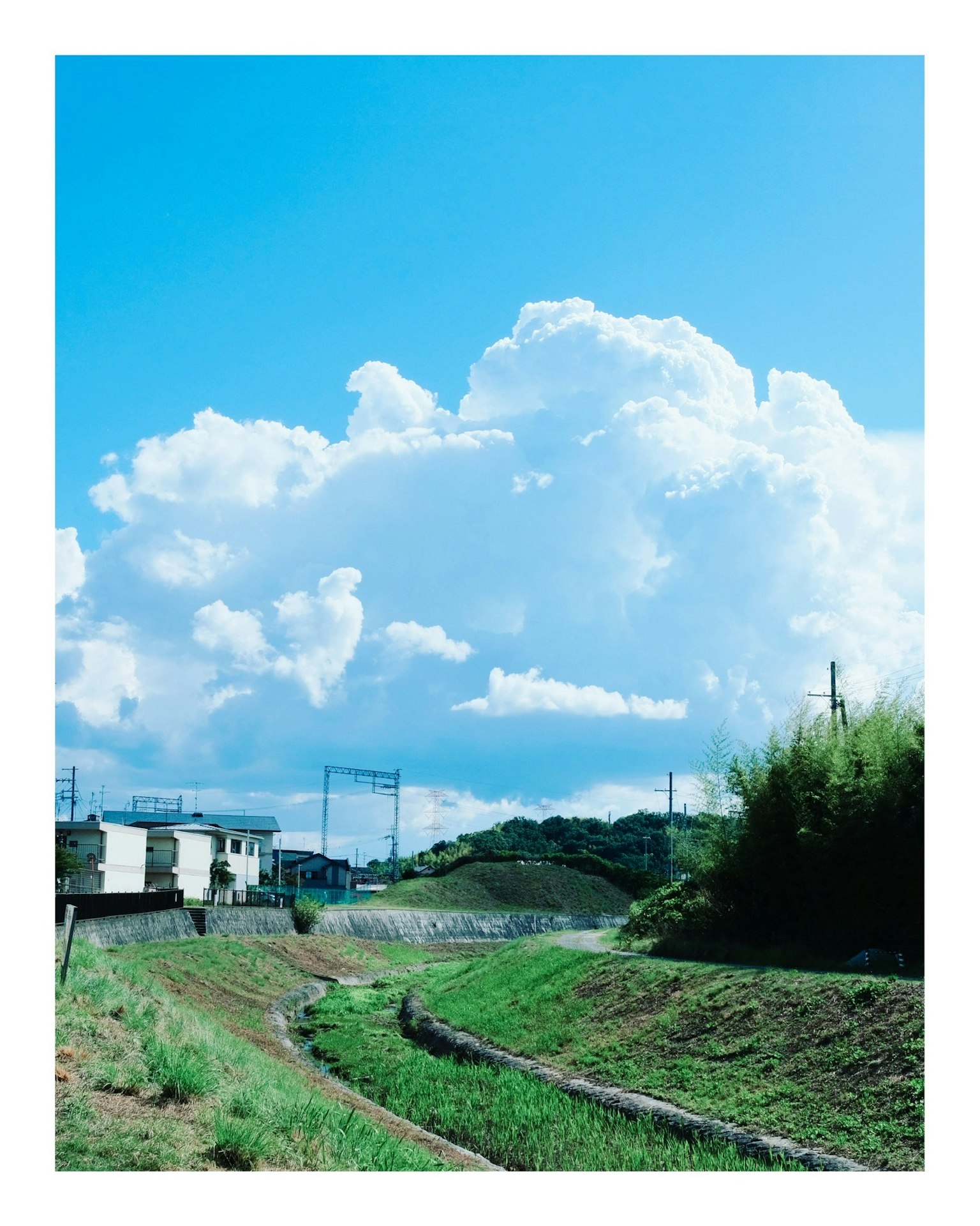 Landschaft mit blauem Himmel und weißen Wolken, die einen gewundenen Weg zeigt