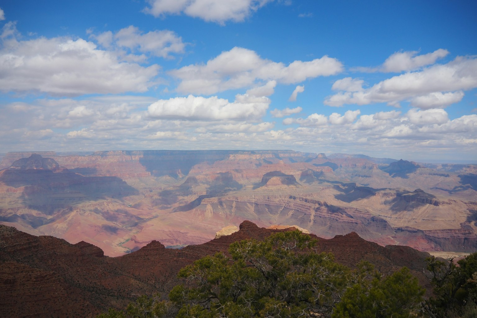 Cảnh quan rộng lớn của Grand Canyon với bầu trời xanh và mây trắng