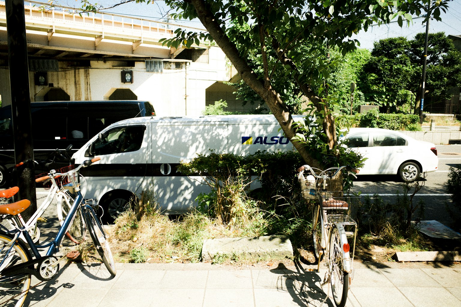 停在綠樹和自行車旁的白色貨車