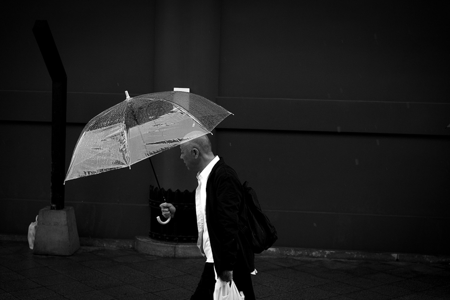 黑白照片，男人在黑暗背景下走路，手持雨伞
