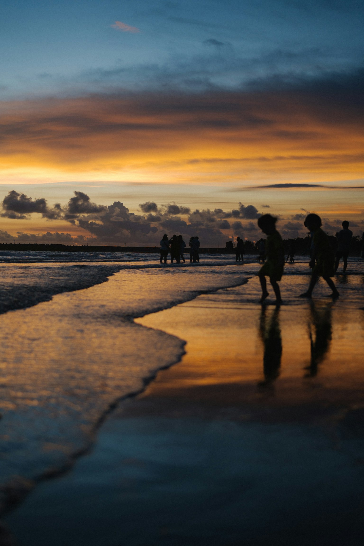 เงาคนเดินอยู่ที่ชายหาดในยามพระอาทิตย์ตกพร้อมกับการสะท้อน