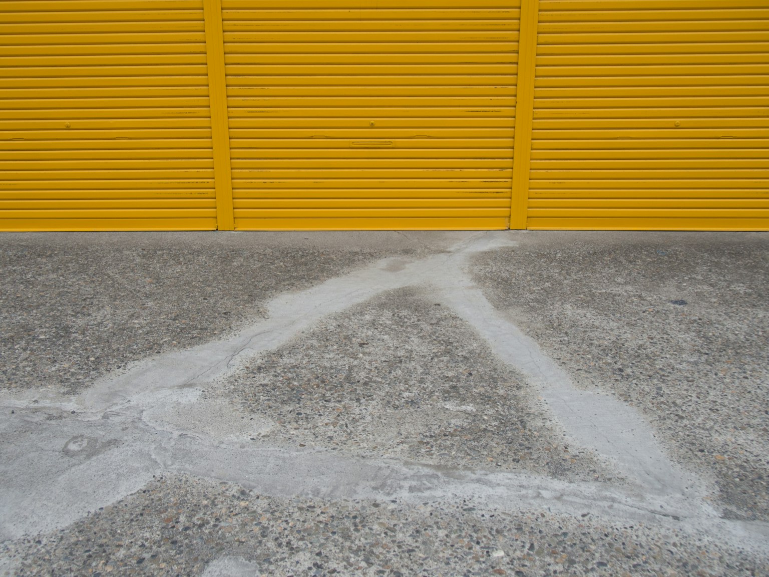 Lantai beton abu-abu dengan garis putih di depan penutup kuning