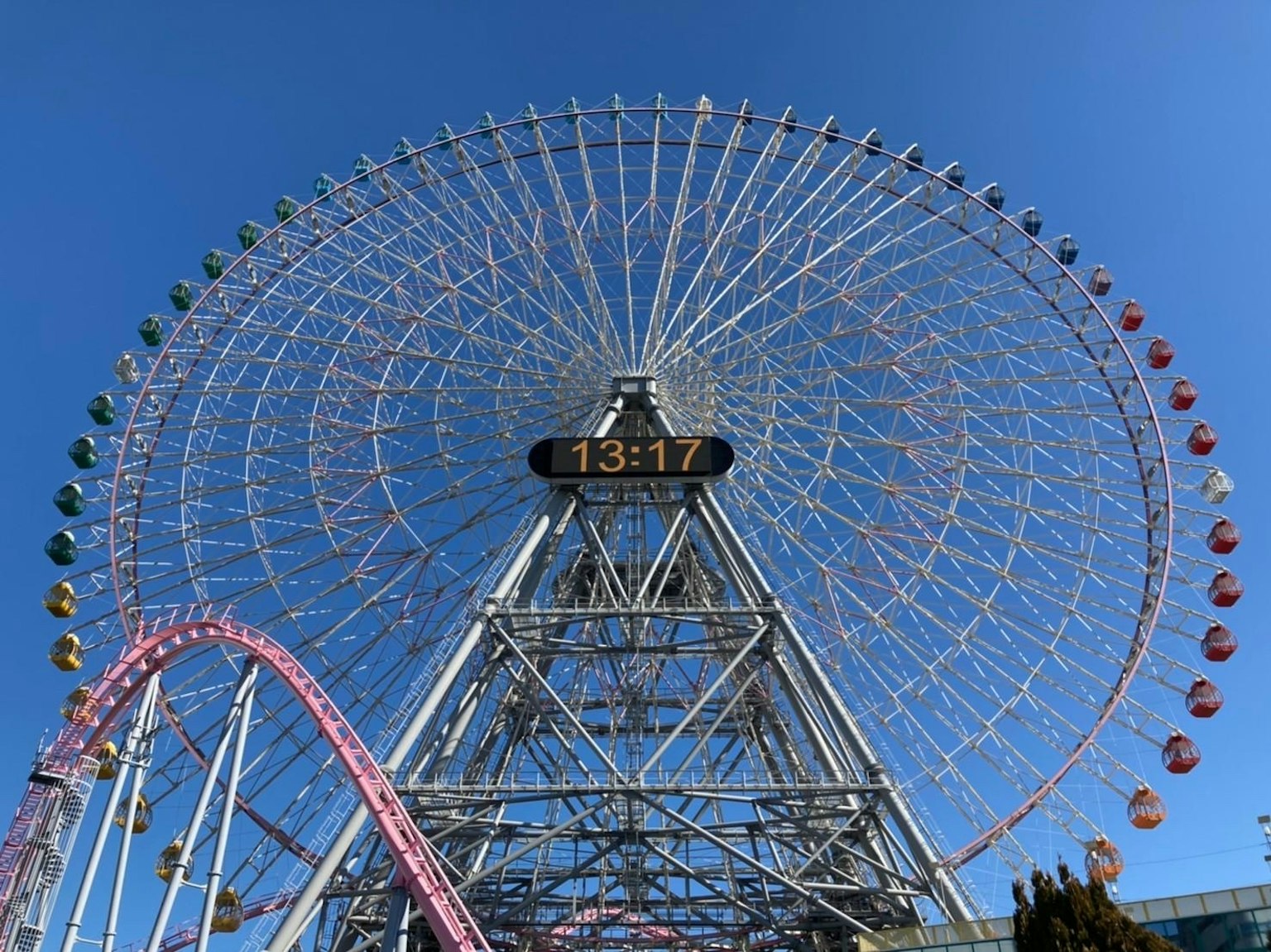 Grande roue et montagnes russes sous un ciel bleu dans un parc d'attractions